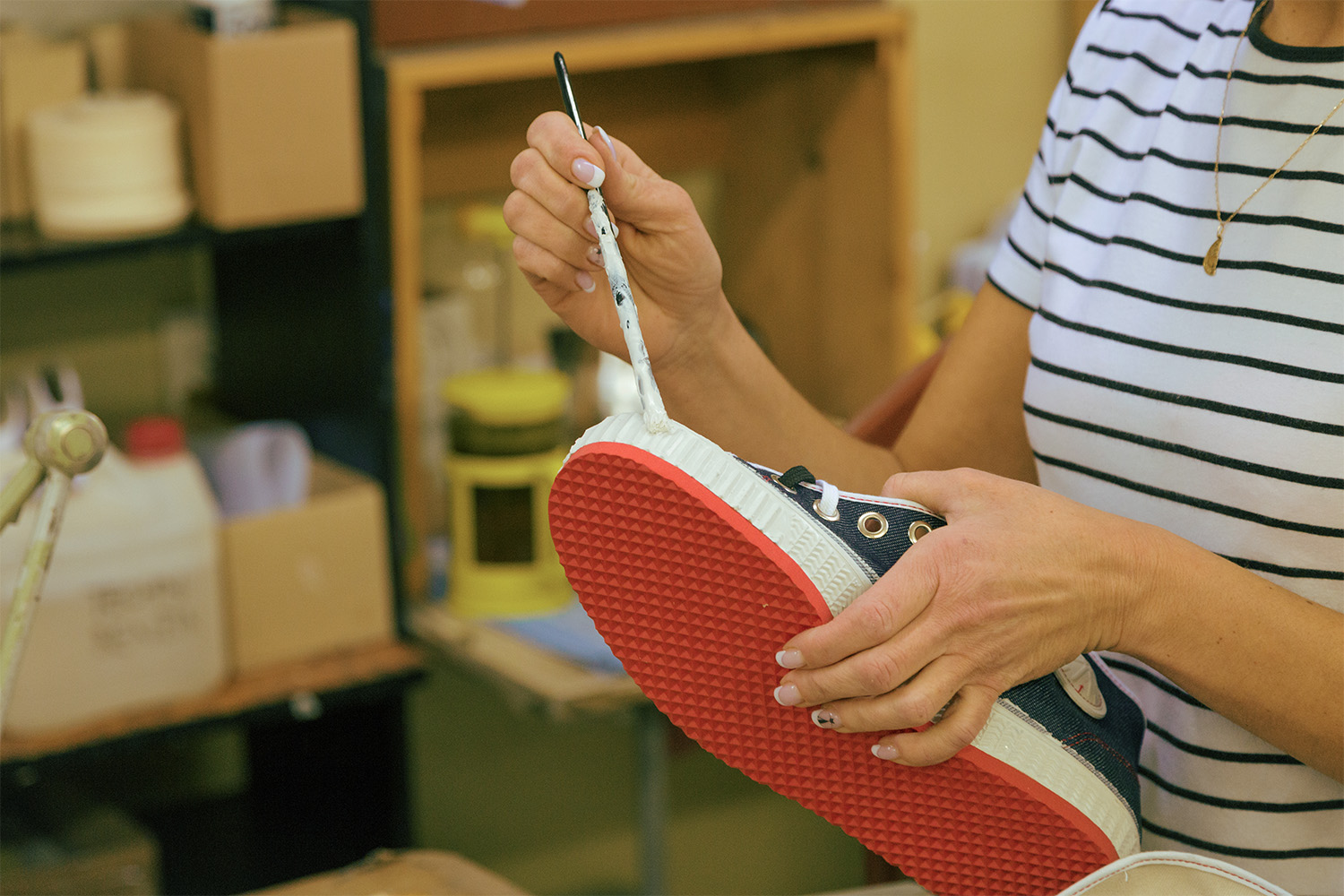 A co-worker finishing the rubber before the shoe has dried. The shoes are then packed for shipping.