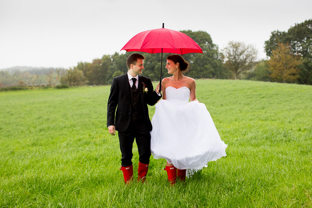  Bryllup i regnvær. Brudepar med matchende rød paraply og røde støvler.&nbsp; 