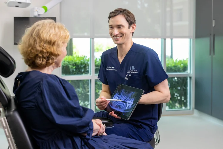 Oral surgeon consulting a patient with digital X-rays on a tablet