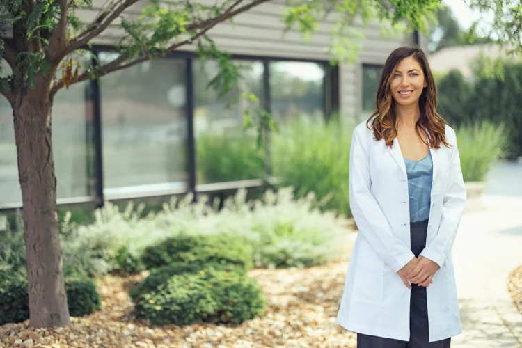 Female healthcare professional in a white coat, outdoor portrait