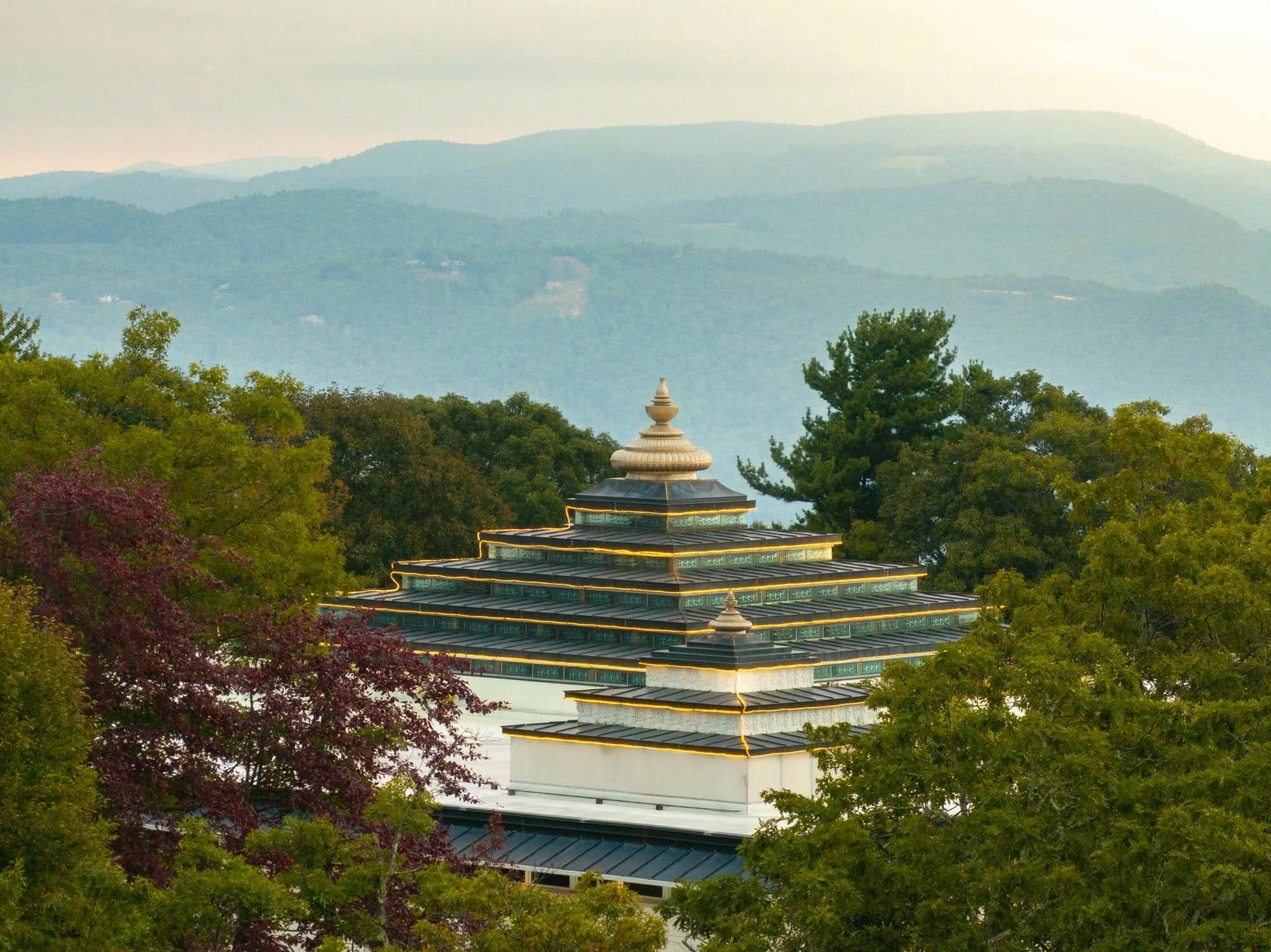 View of a multi-tiered pagoda surrounded by trees in a mountainous landscape.