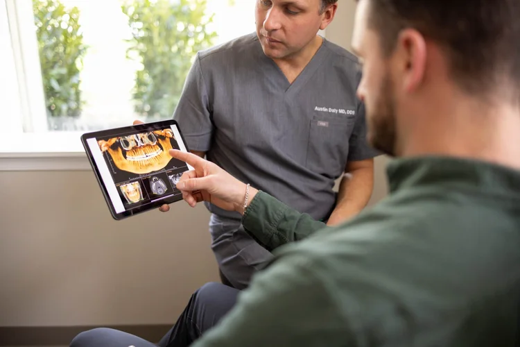 Dentist and patient reviewing dental X-rays on a tablet