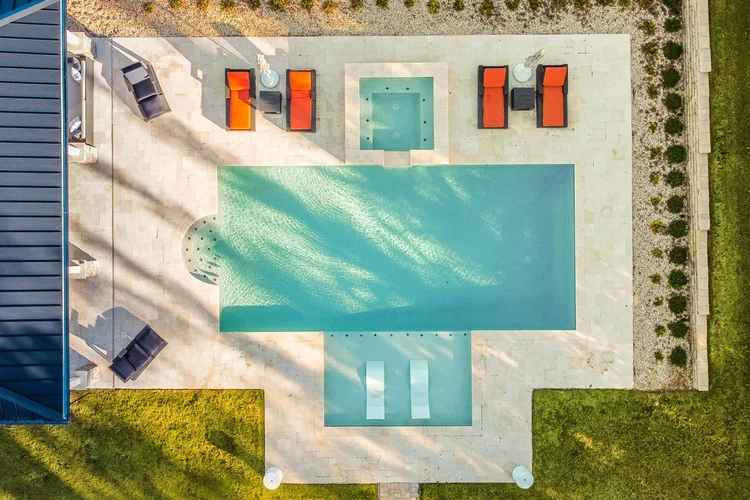 Aerial view of a backyard swimming pool with lounge chairs, a hot tub, and landscaped desert surroundings.