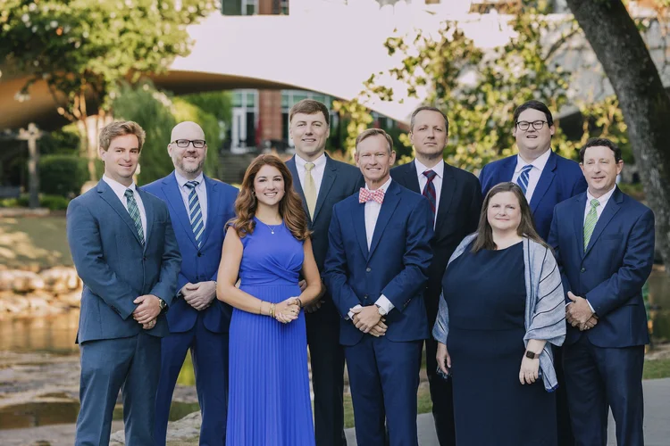 Ten-person law office team portrait by a pond