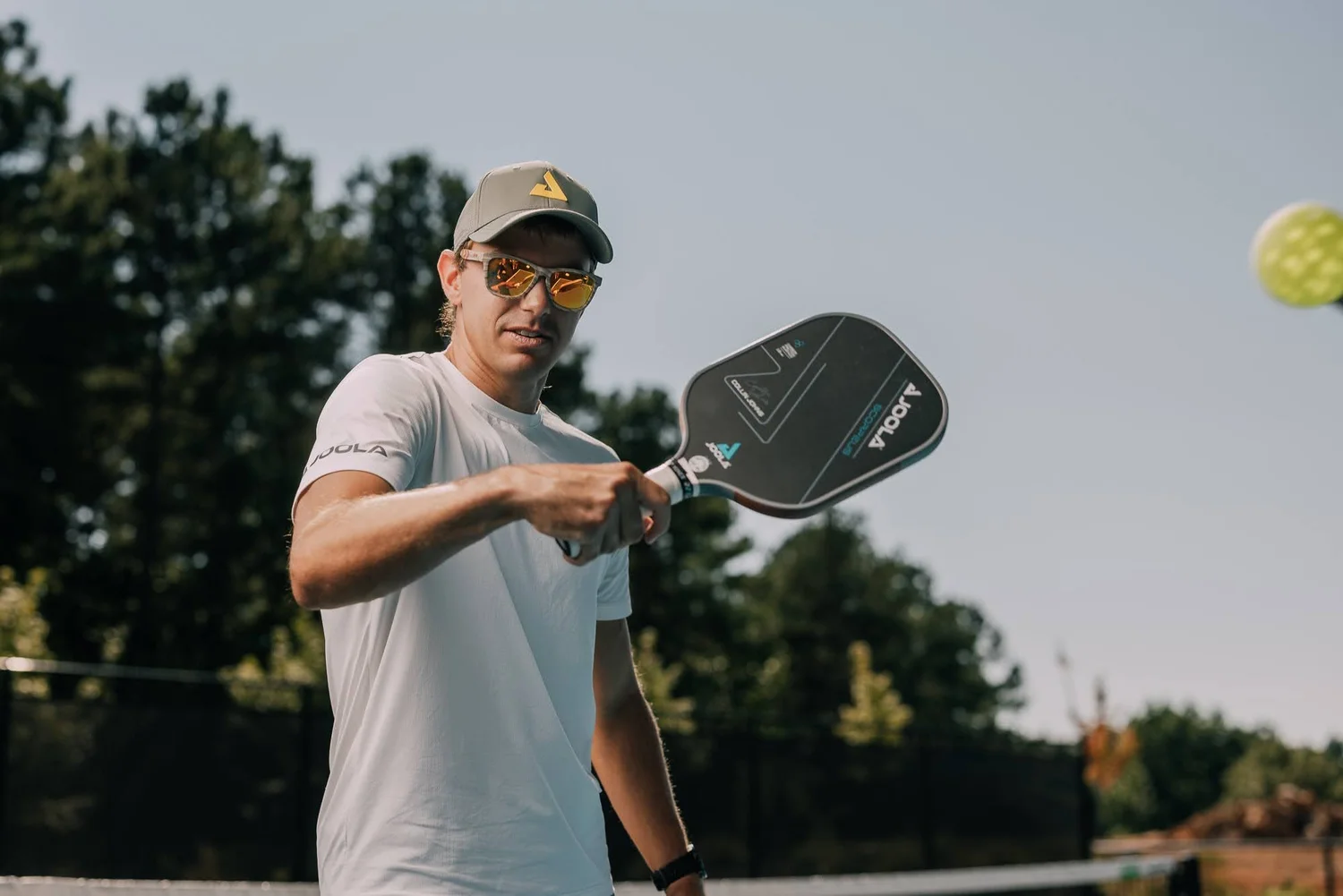Professional pickleball champion Collin Johns mid-swing on court at a Cliffs clinic, outdoor event photography by Jack Robert