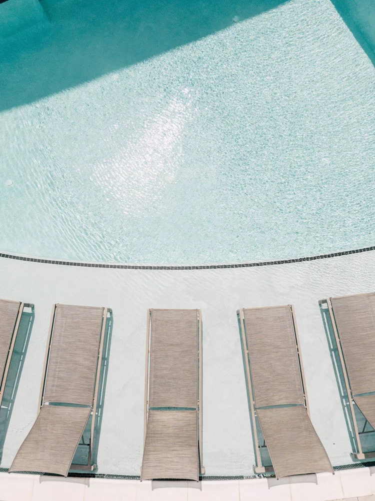 Aerial view of a swimming pool with four lounge chairs on the pool deck.