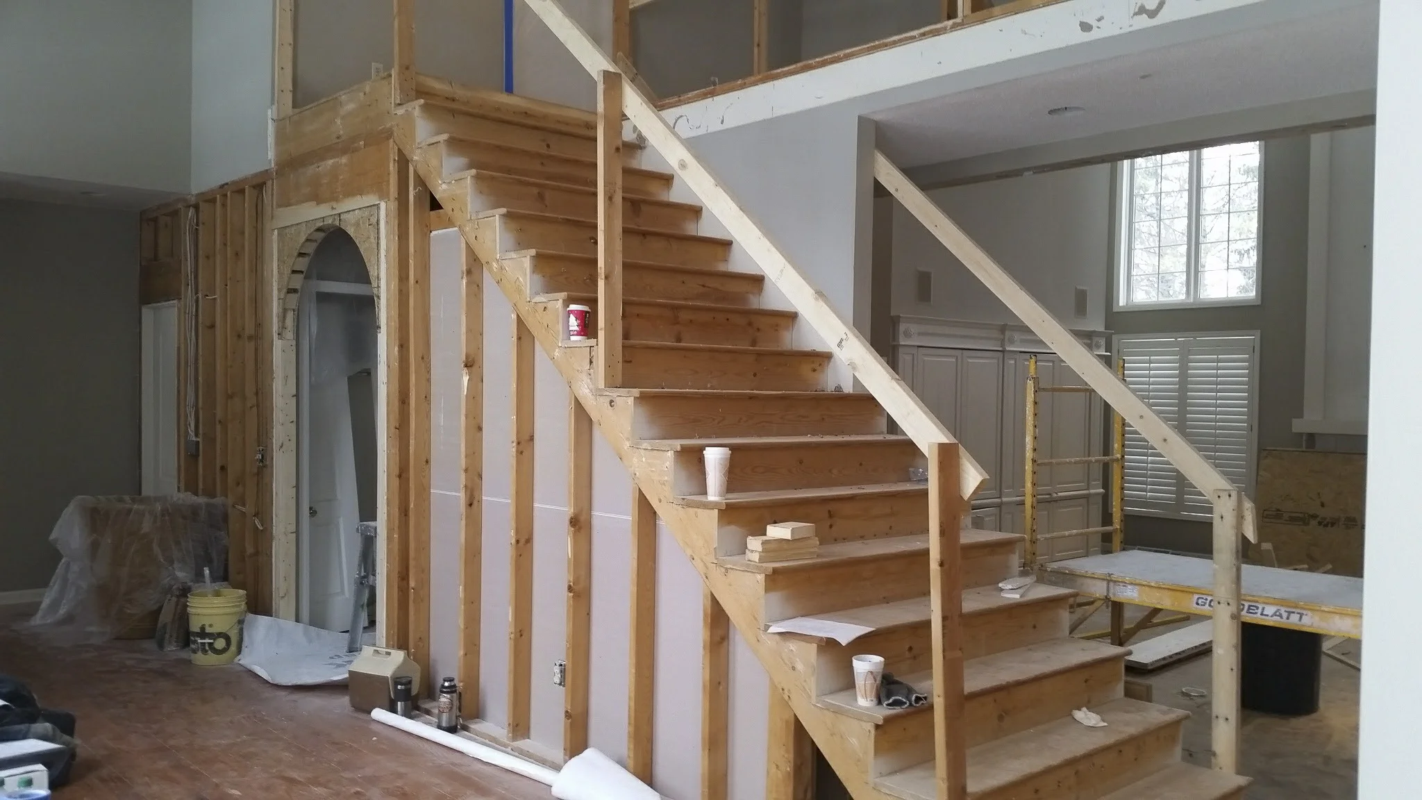 Carpeting, railings and drywall removed from stairway and foyer walls. Arched opening framed in. 