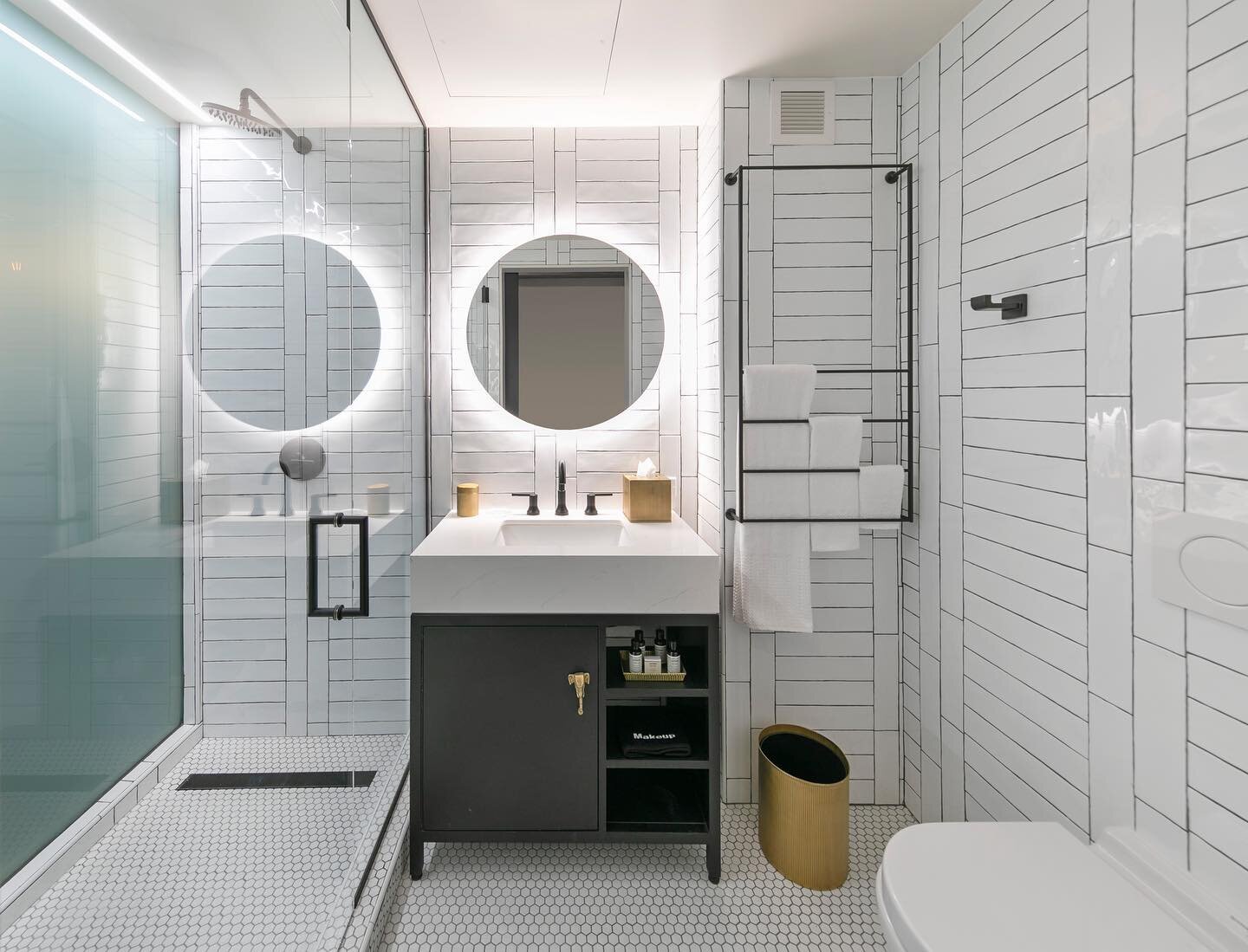 Materiality can impact how one perceives space. At the @WayfarerDTLA the use of translucent glass between the shower and guest room allowed for evenly diffused natural daylight to pour into the bathroom. White tile surfaces help bounce the light off 