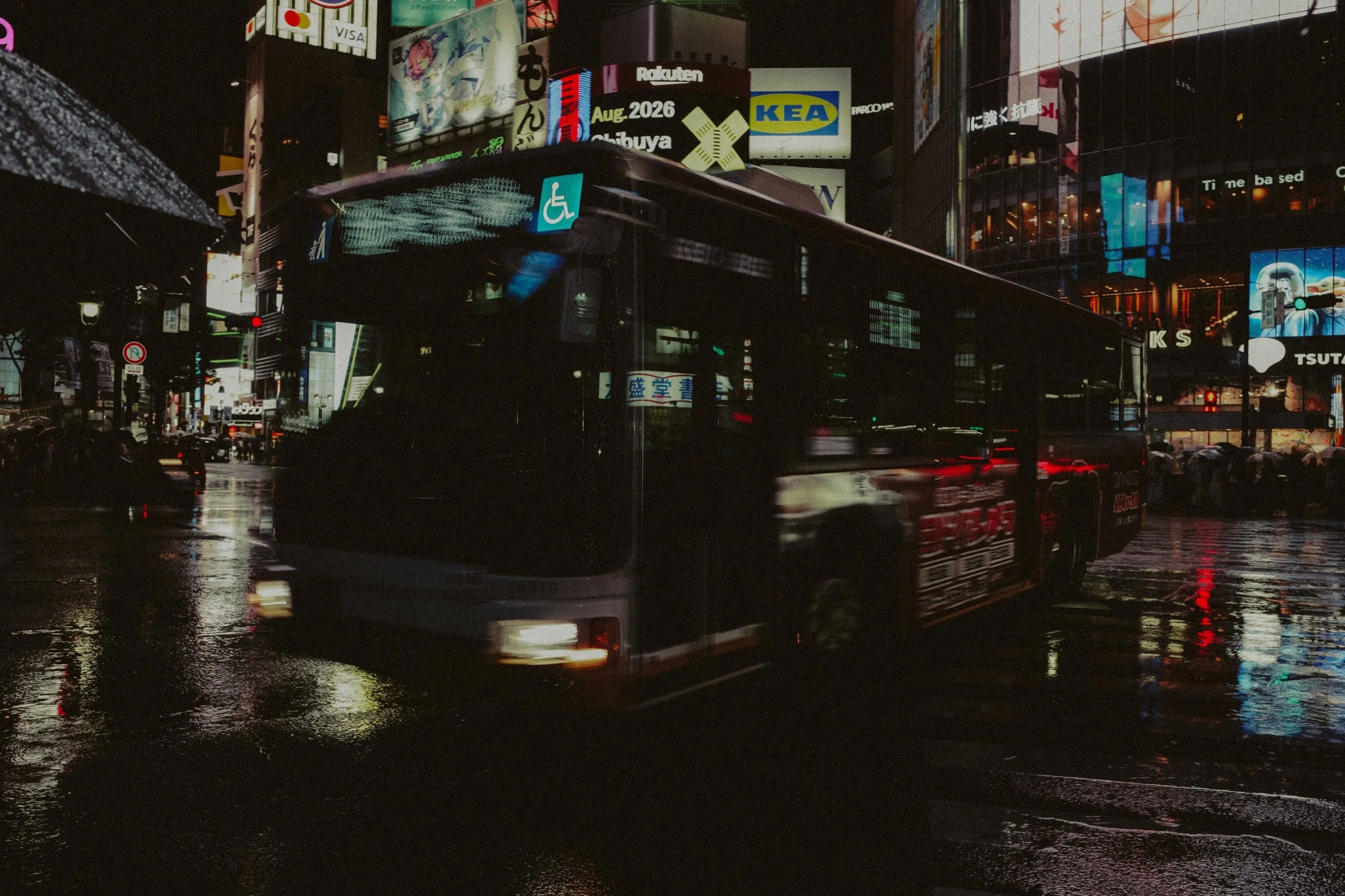 Tokyo — a bus crossing a rain-soaked street at night