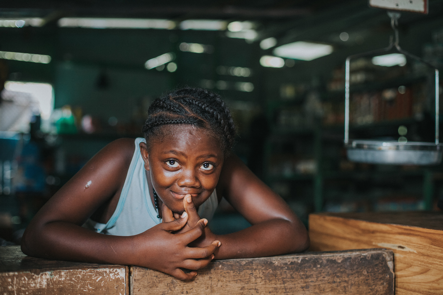  Young girl leans against the counter of her family's store with her mother close by as they wait for more business to come in. 