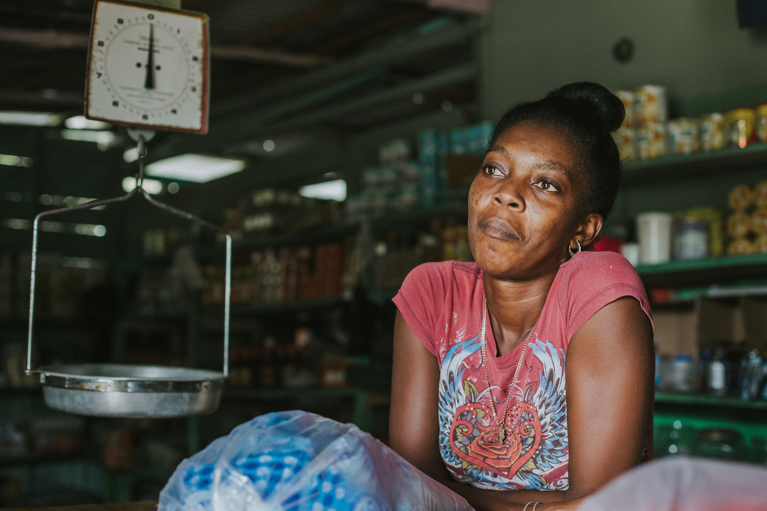 Local store owner gazes out her front window. Her store is the only place in the village to sell such a large variety of foods.