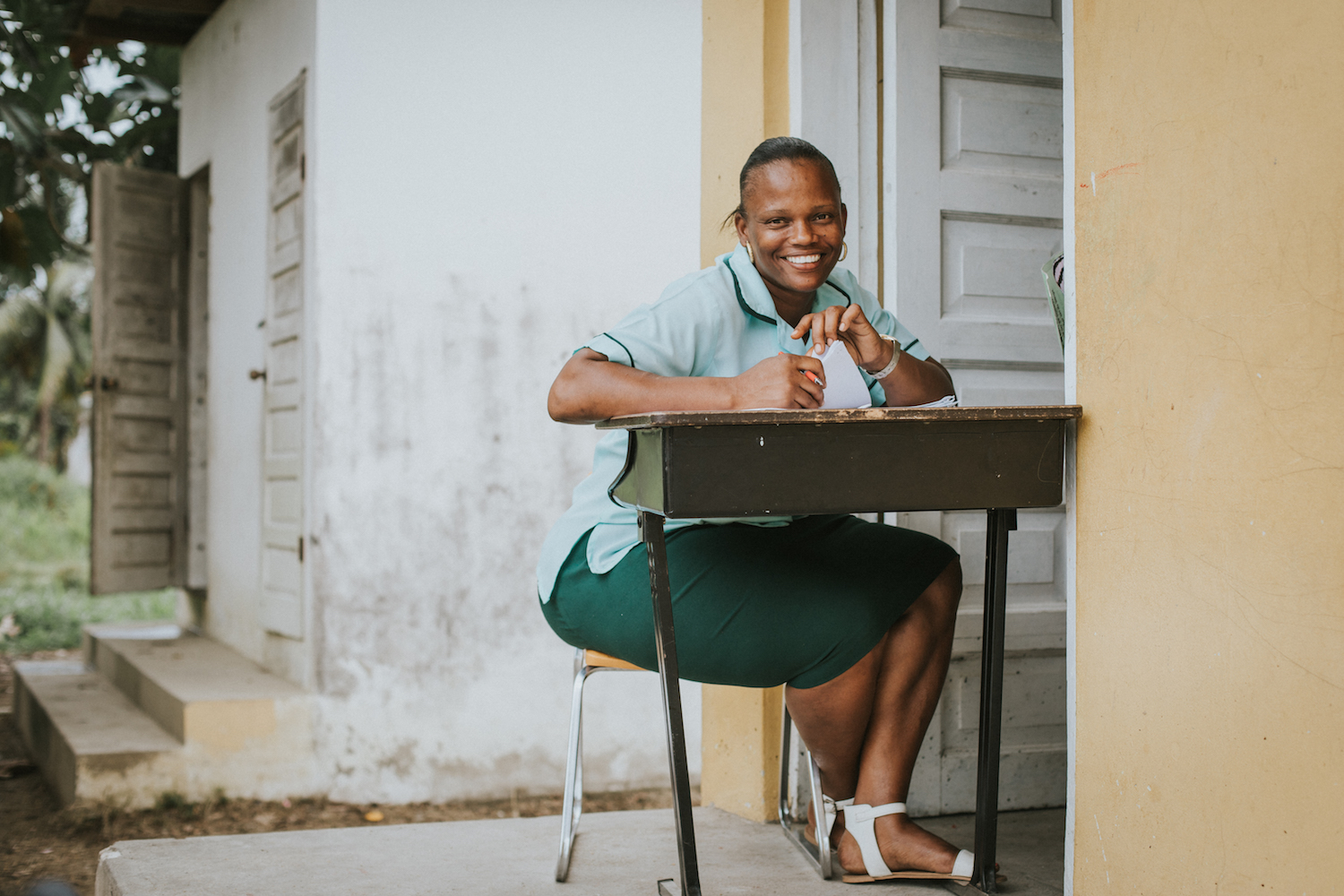  In nearby Dangriga, the capital of Belize's Stann Creek District, a young teacher poses for a photo while class is still in session inside the schoolhouse. 