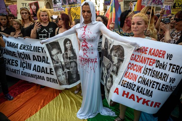 Protesters in Istanbul including an LGBT supporter painted with red tears symbolising blood, her dress.