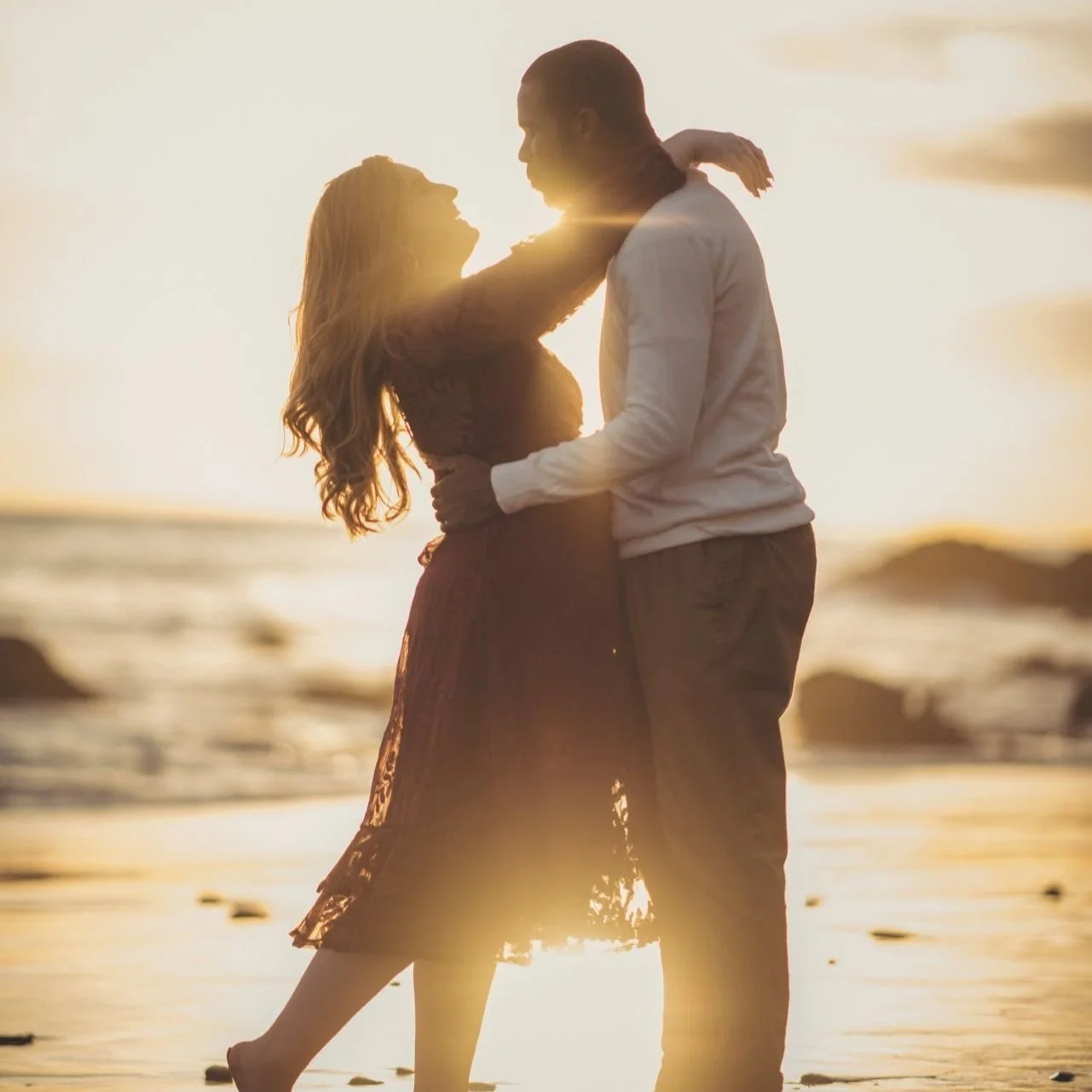 Silhouette of a couple embracing on a malibu beach at sunset.