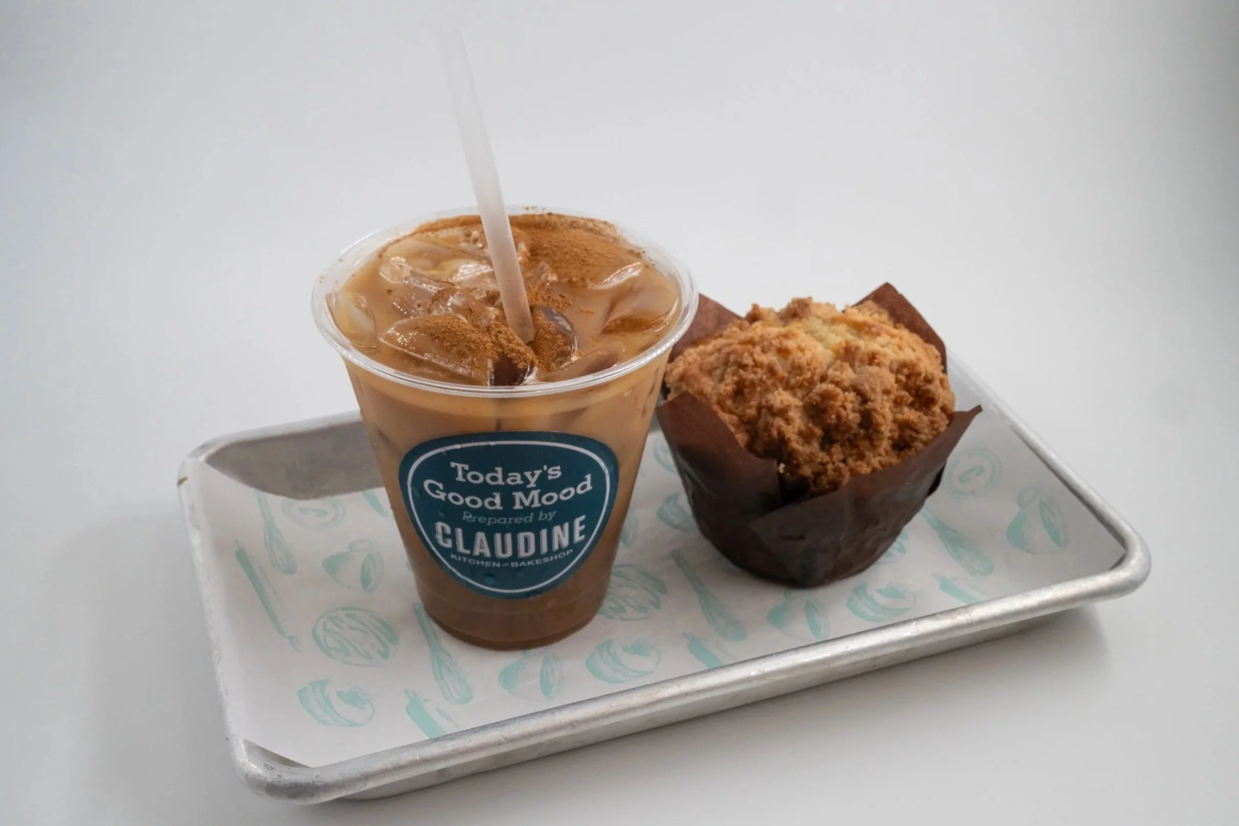 Iced coffee with cream and cinnamon, and a muffin on a tray