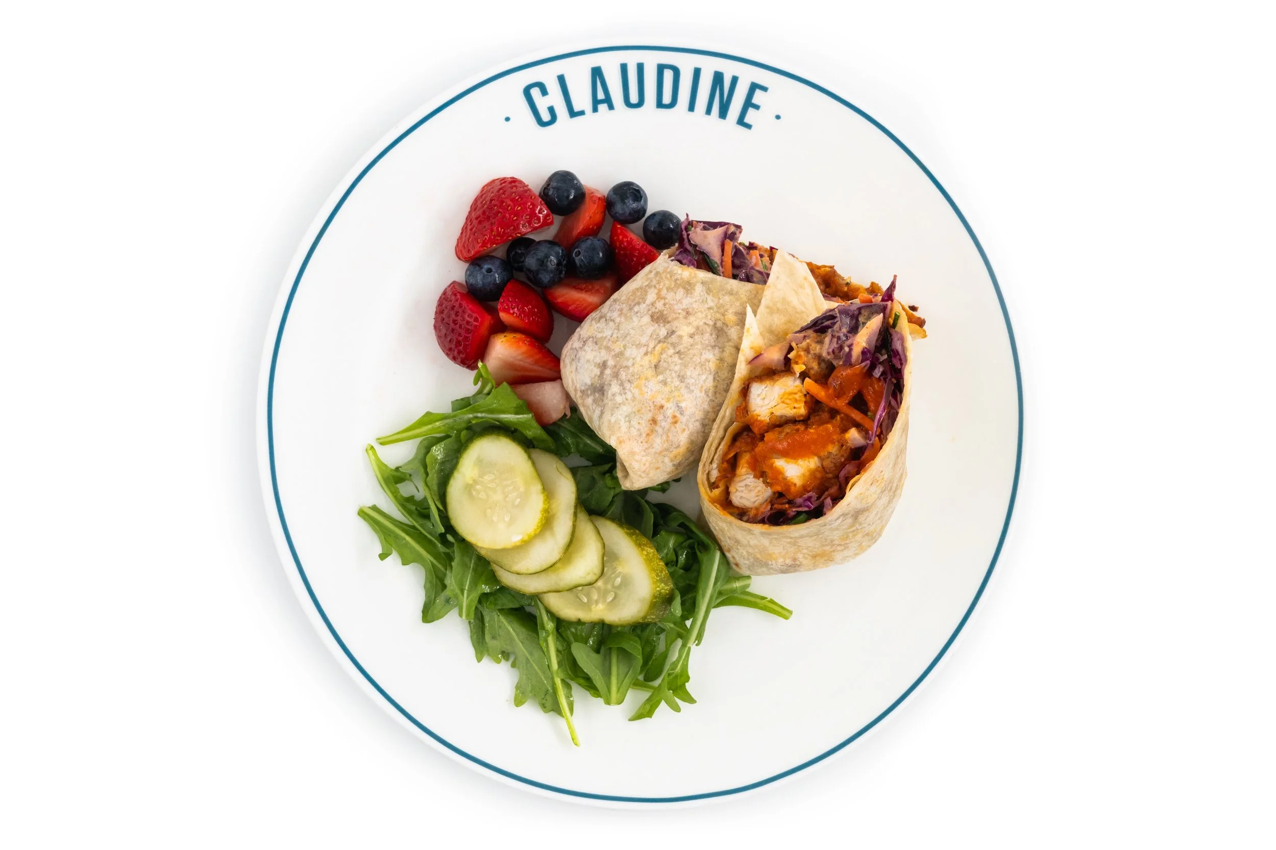 Plate with two spring rolls, mixed berry fruit, and a small side salad with cucumber slices and arugula. The plate has 'Claudine' written on the rim.
