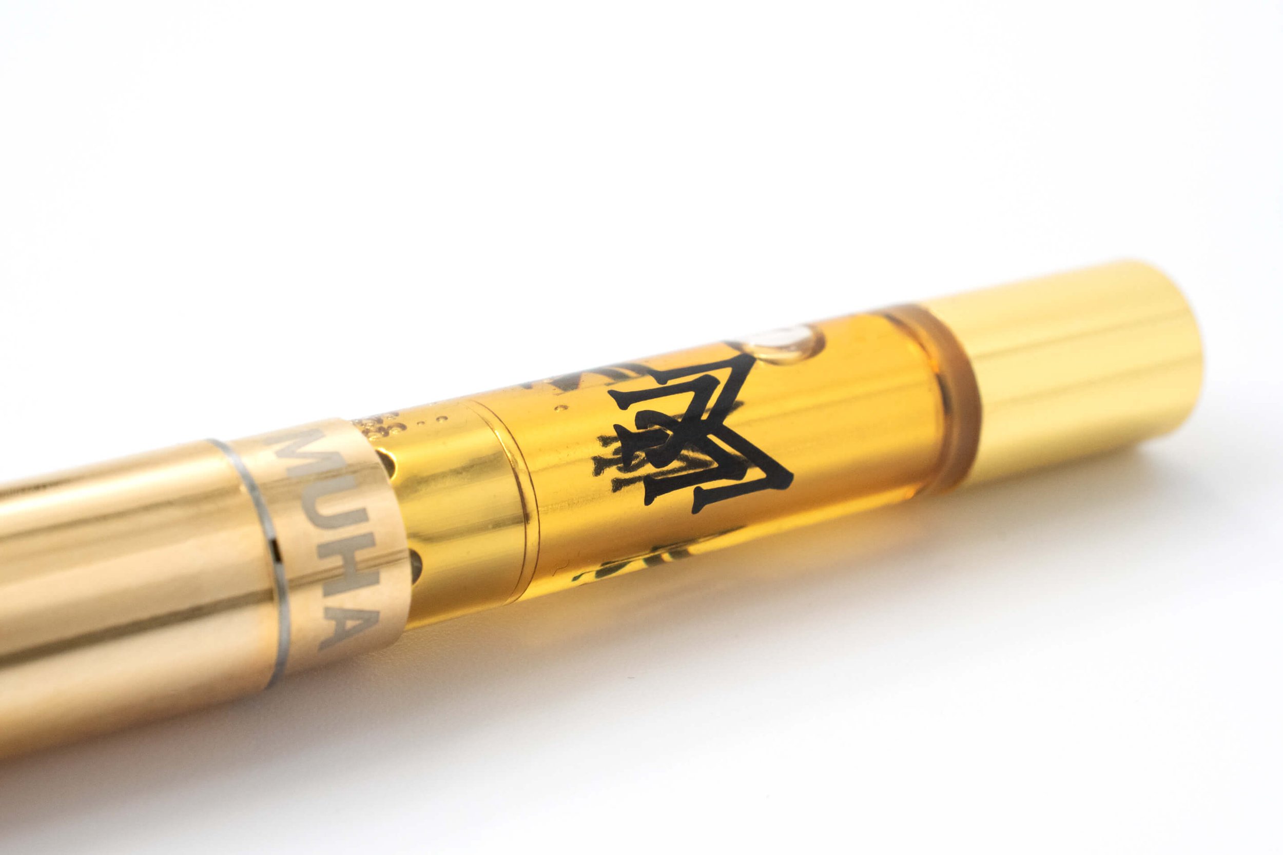 Vape cartridge with golden liquid and gold metal accents on white background