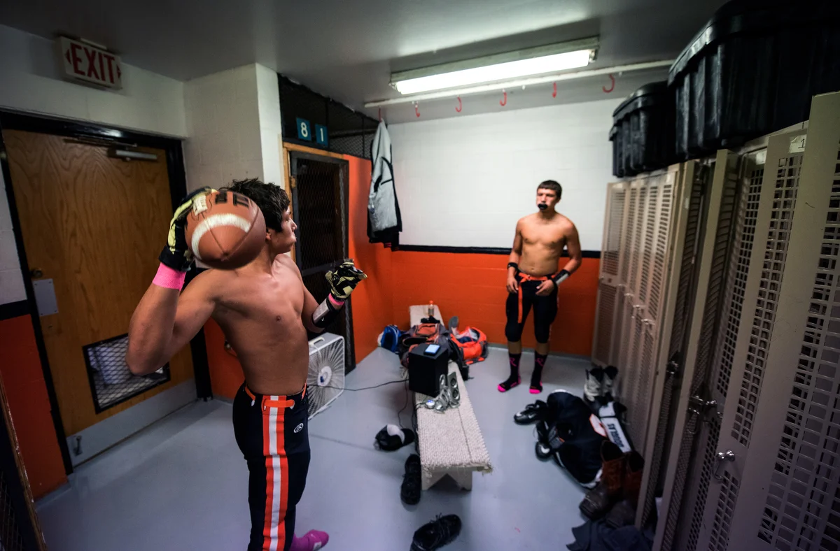 Arvidis Henry and Dawson Gourd toss a football back and forth in the locker room before the game. The space the two players take up is about half the locker room.