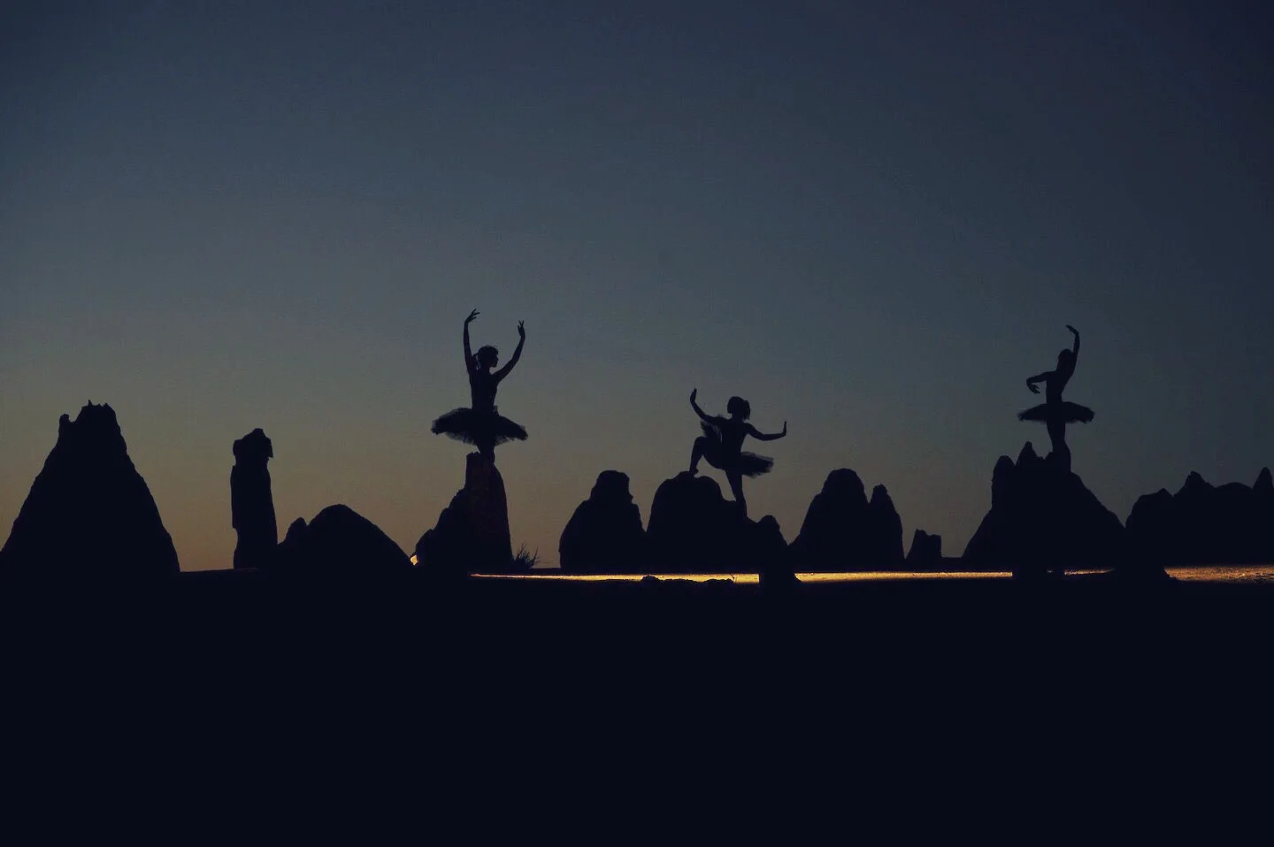 A still frame of the dancers at dusk, light from a dedo sstreamingg past them.