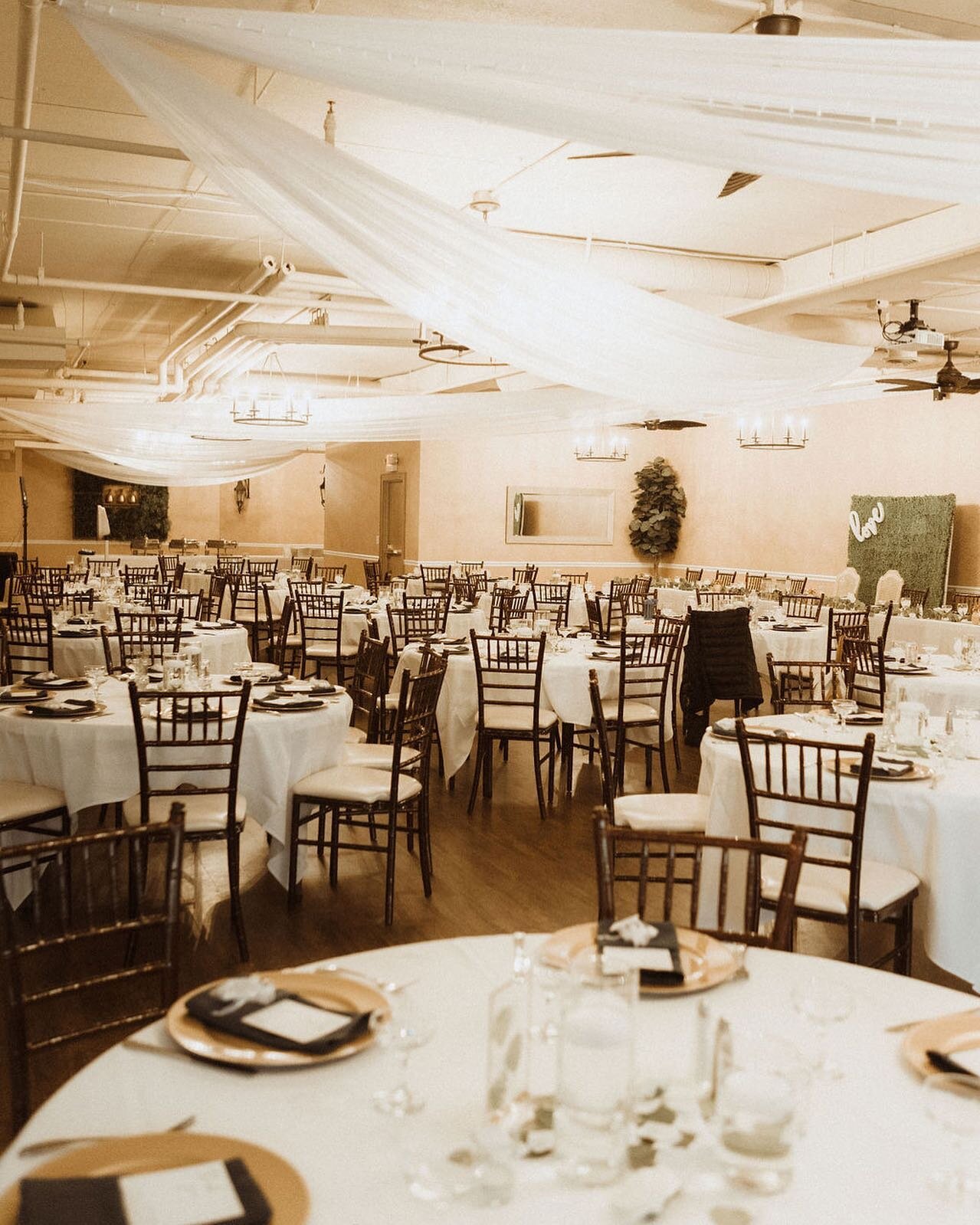 Mahogany chivari chairs, wooden floors, round tables, and iron chandeliers are come of the features of our timeless ballroom. 

Photo: @eandephotoandfilm 
Lighting and Draping: @granddesignsmn 
#chivarichairs #weddingreception #weddingdraping #chande