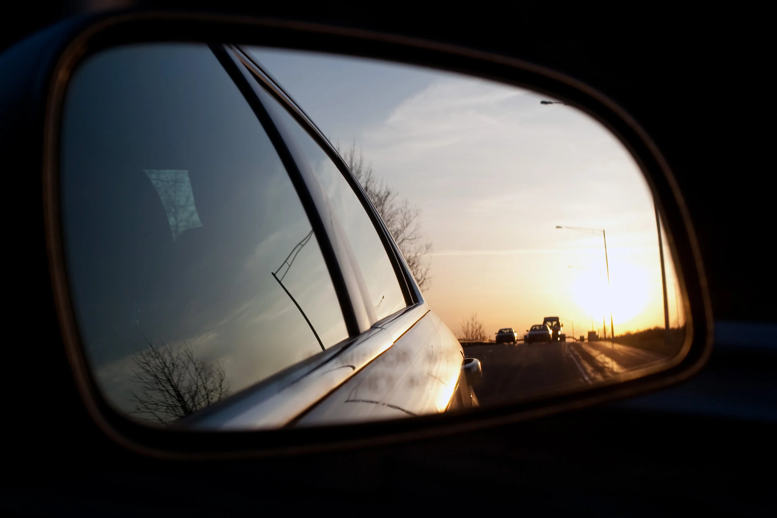 view-of-the-sunset-from-the-side-view-mirror-of-a-car-while-driving-down-the-road-shallow-depth-of-field-great-image-for-illustrating-blind-spots_StWbrsv0Ho.jpg