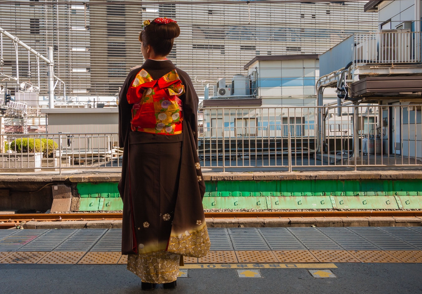  A woman wearing a beautiful kimono waits for a train at Shinjuku Station 