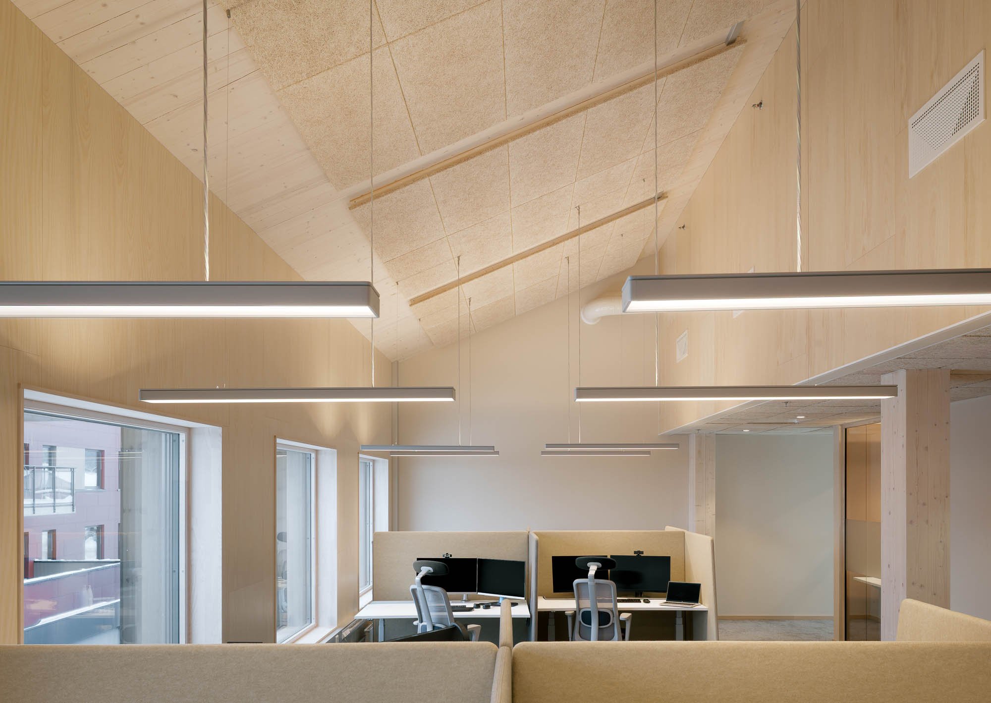 Moderne kontor med arbeidsstasjoner, skjermer, stillerom og store vinduer med utsikt.