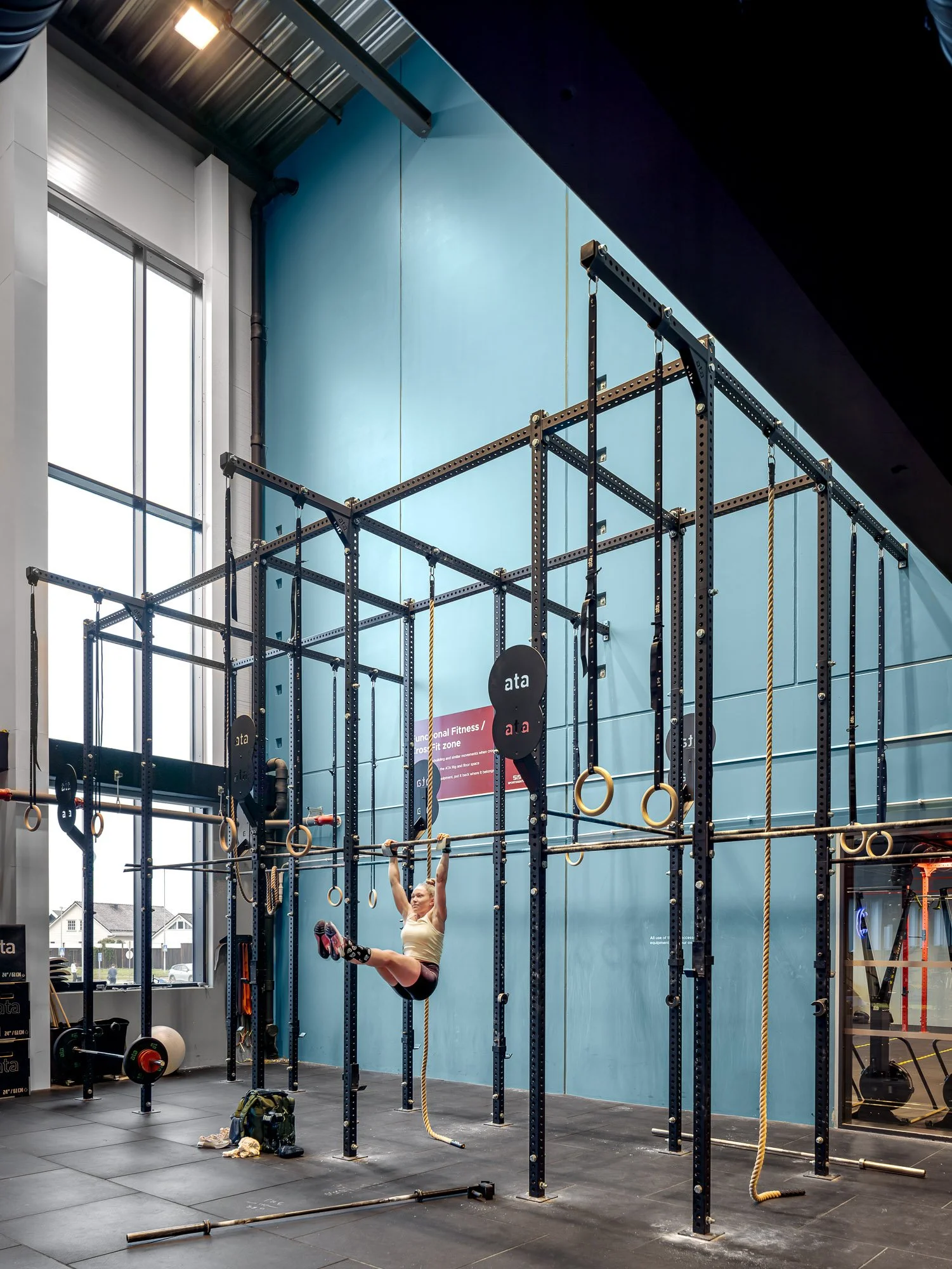 Kvinne som trener i et treningsstudio med tau og sirkler, store vinduer i bakgrunnen.