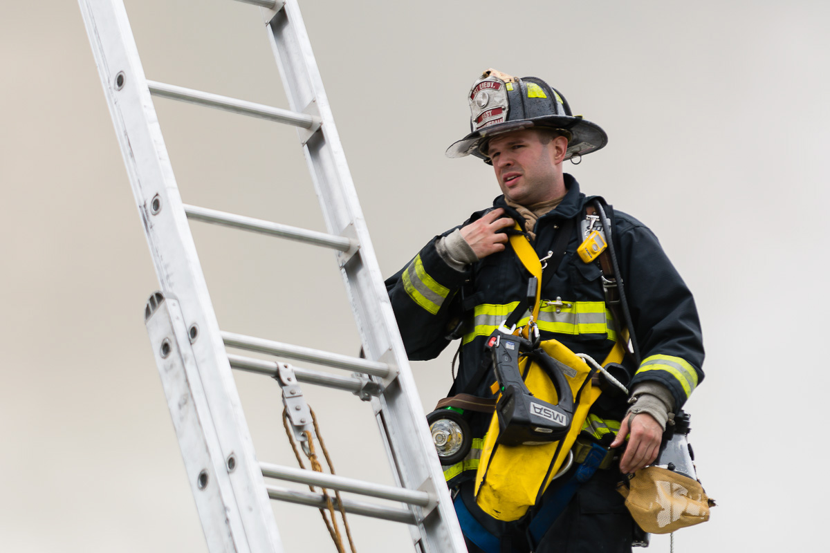 East Farmingdale Fire Company Lieutenant Jason Frankel observes a fully involved warehouse in Wyandanch from atop an adjacent building on May 17, 2016.