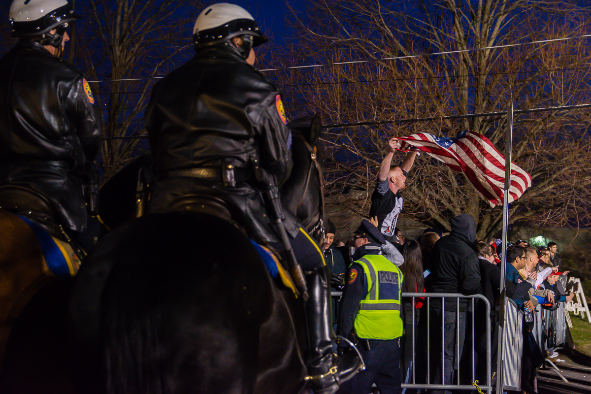 A Donald Trump supporter waves an American flag on Wednesday April 6, 2016 outside Trump's Bethpage, Long Island, rally. Moments after this frame was taken Nassau County Police had to deploy mounted officers and riot control officers to break up altercations between Trump supporters and protesters .