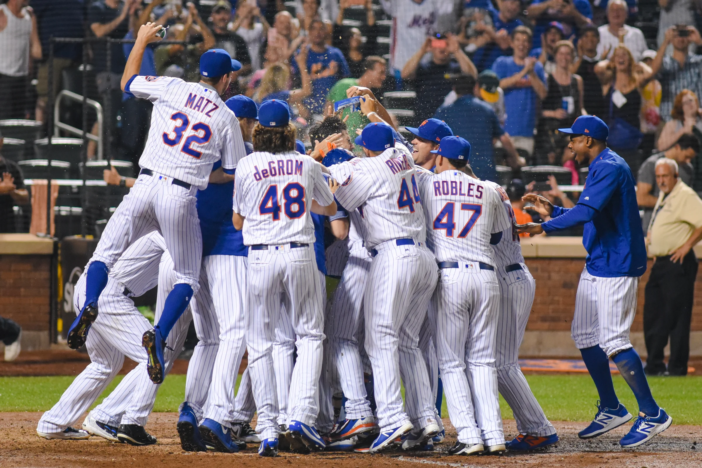 New York Mets infielder Wilmer Flores gets mobbed at home plate after hitting a two-out, walk-off home run in the bottom of the ninth inning to lead the Mets over the Oakland Athletic's, 6-5, at Citi Field on July 22, 2017.