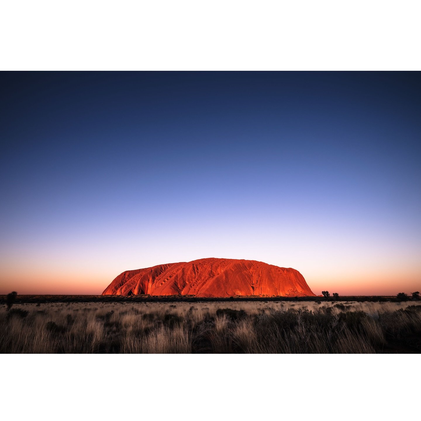 Uluru Sunset - July, 2025

I arrived early at my carefully chosen spot for the Uluru sunset. The sun was already low but waiting for that perfect moment seemed interminable.  As the shadow crept slowly across the desert grasses, edging closer to Ulur