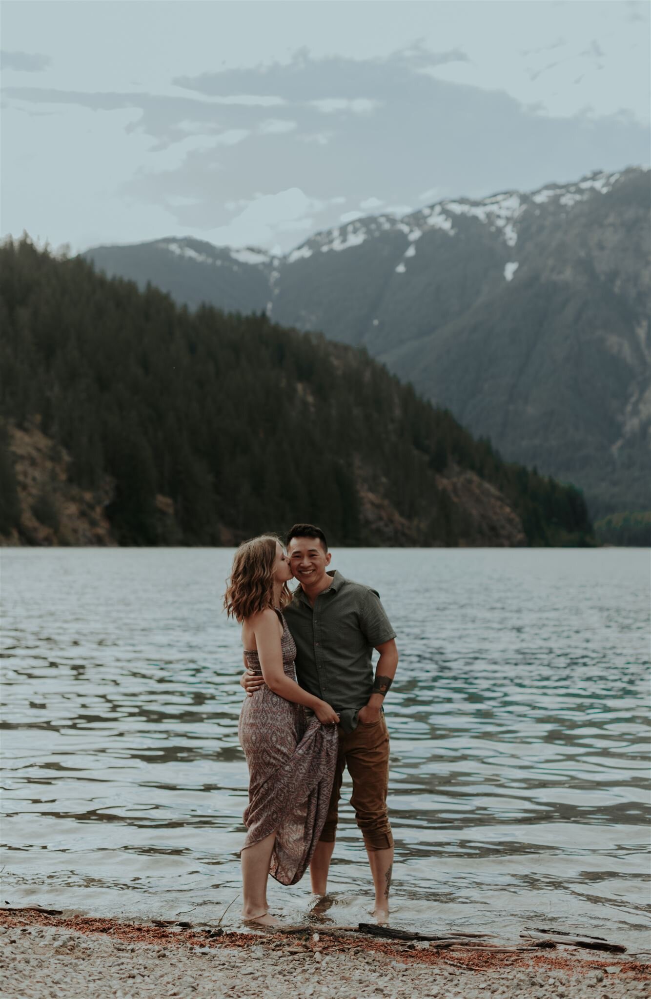  waterside shot of a couple kissing with their toes in the sand 