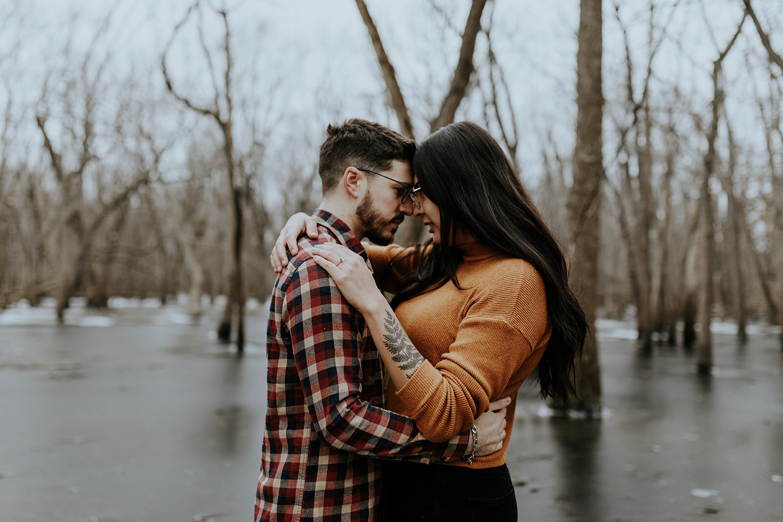  adventurous couple in fall winter clothes on an icy lake staring into each other’s eyes 