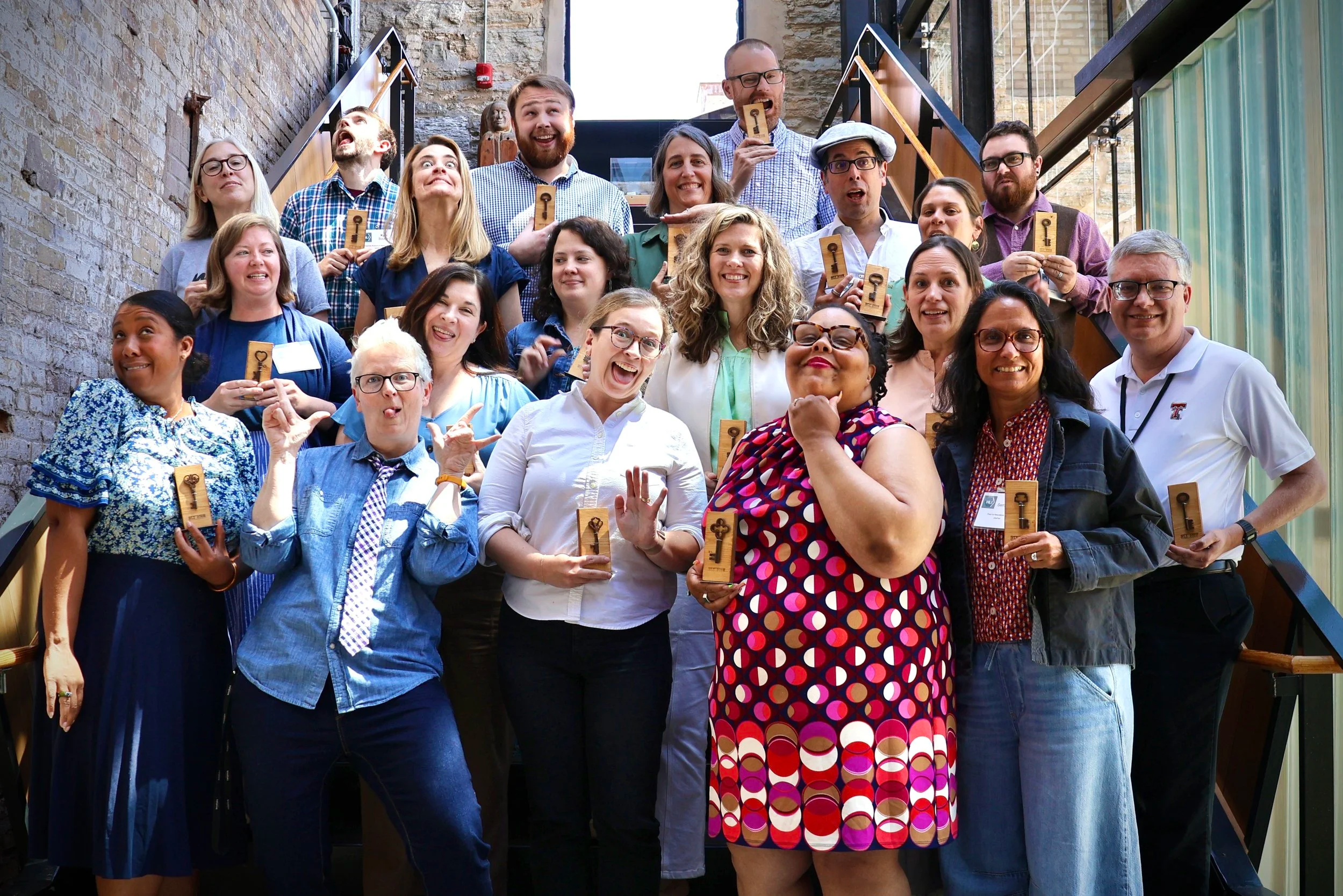 Group shot of 19 History Leadership fellows acting silly. Lined up in 3 rows on a set of stairs