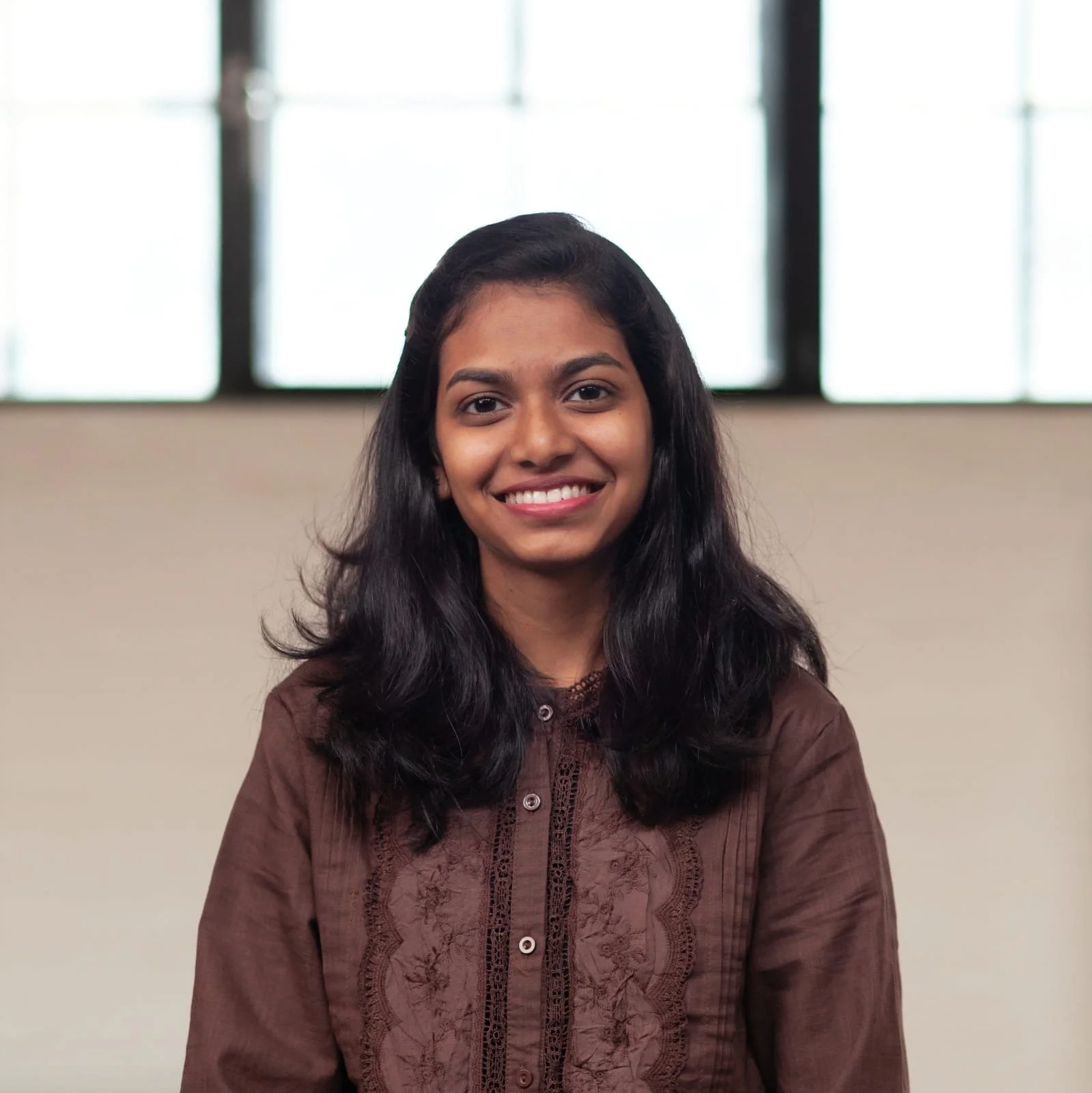A smiling Sahithi Mareedu standing in front of a wall.