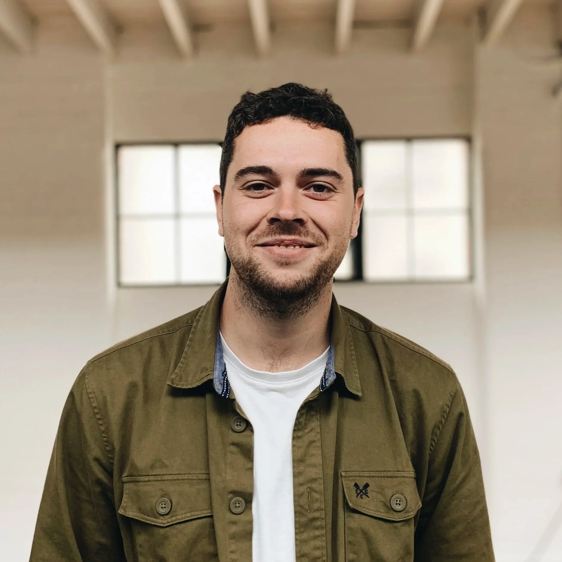 A smiling Matt Proctor standing in front of a wall.
