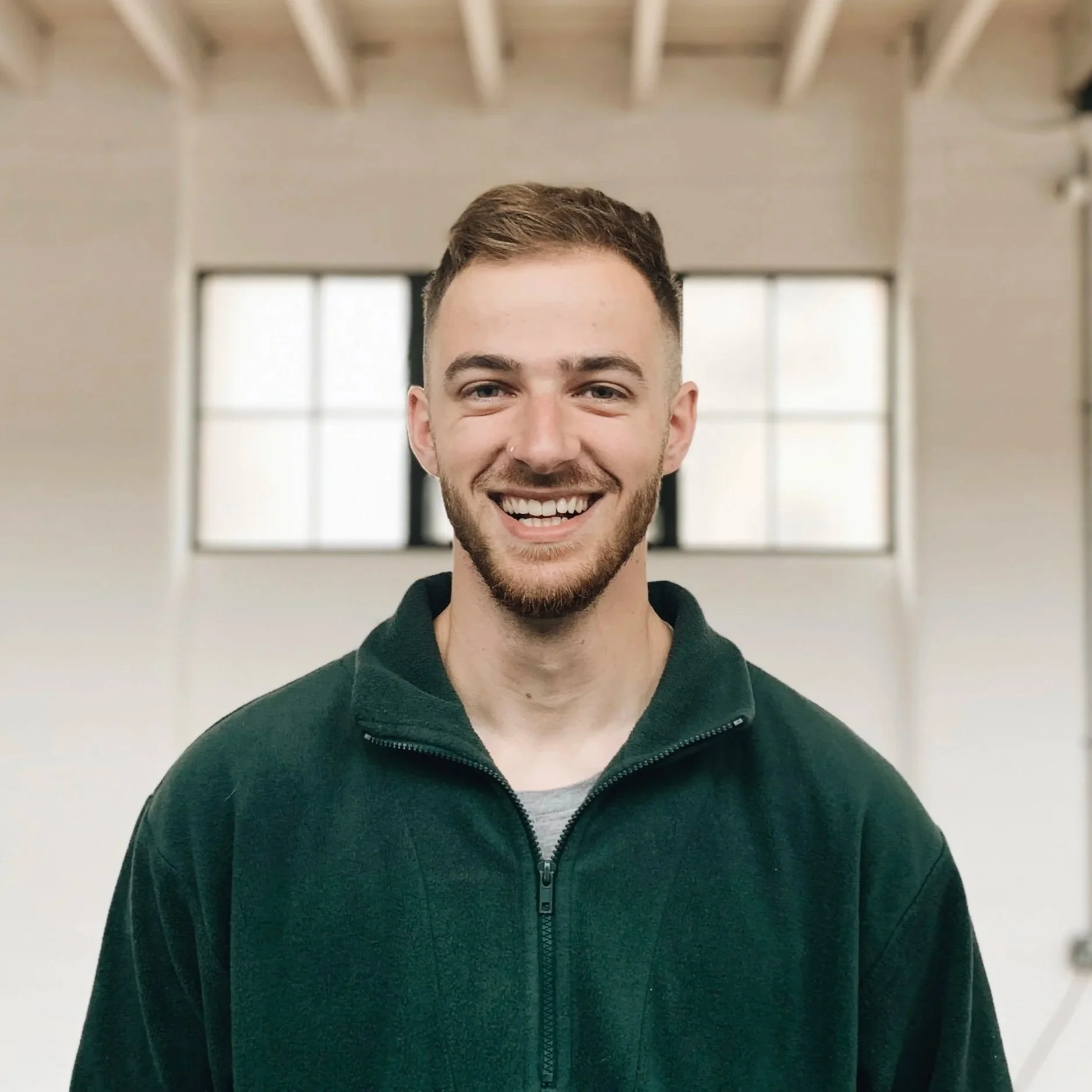 A smiling Dan Grout standing in front of a wall.