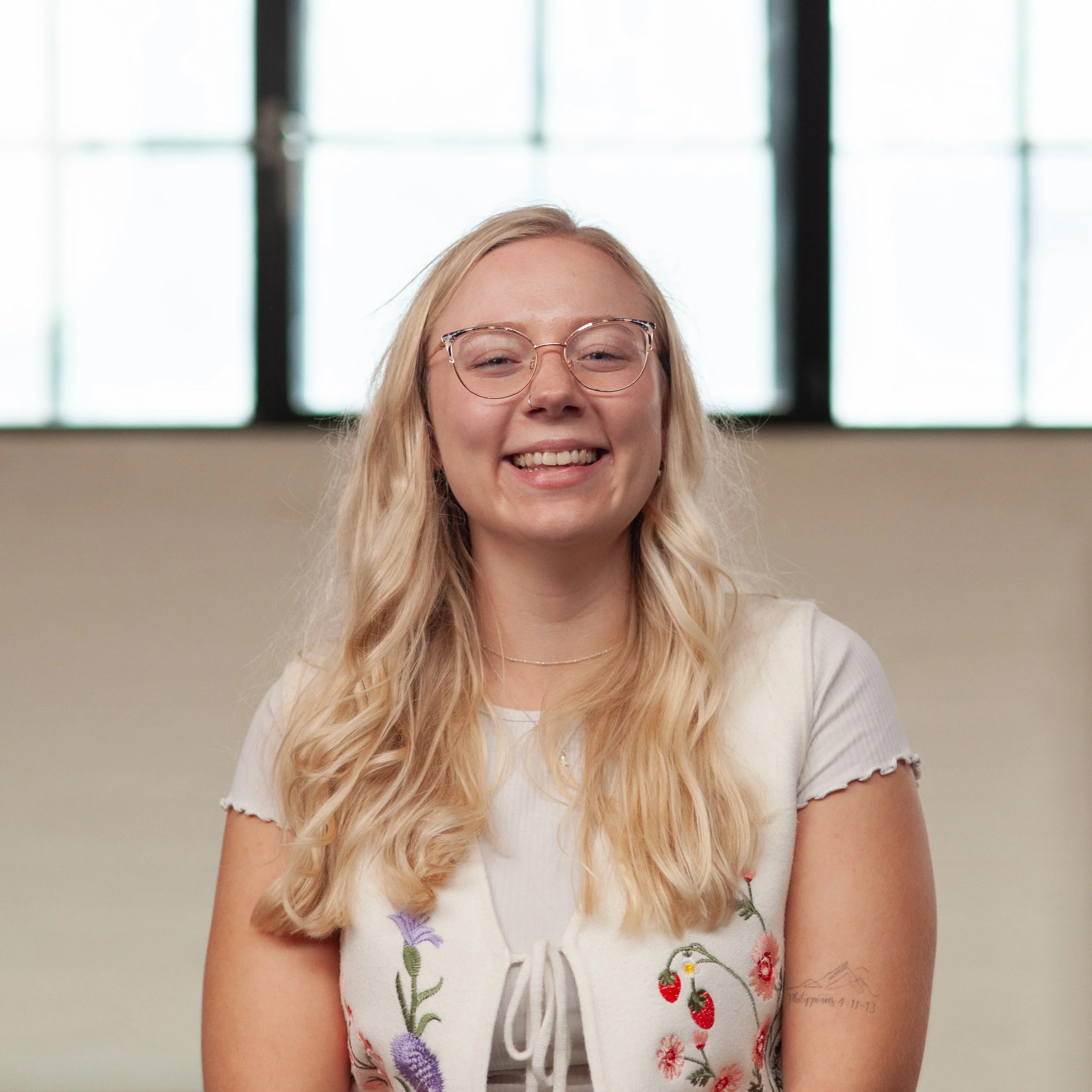 A smiling Sophie Smuts standing in front of a wall.