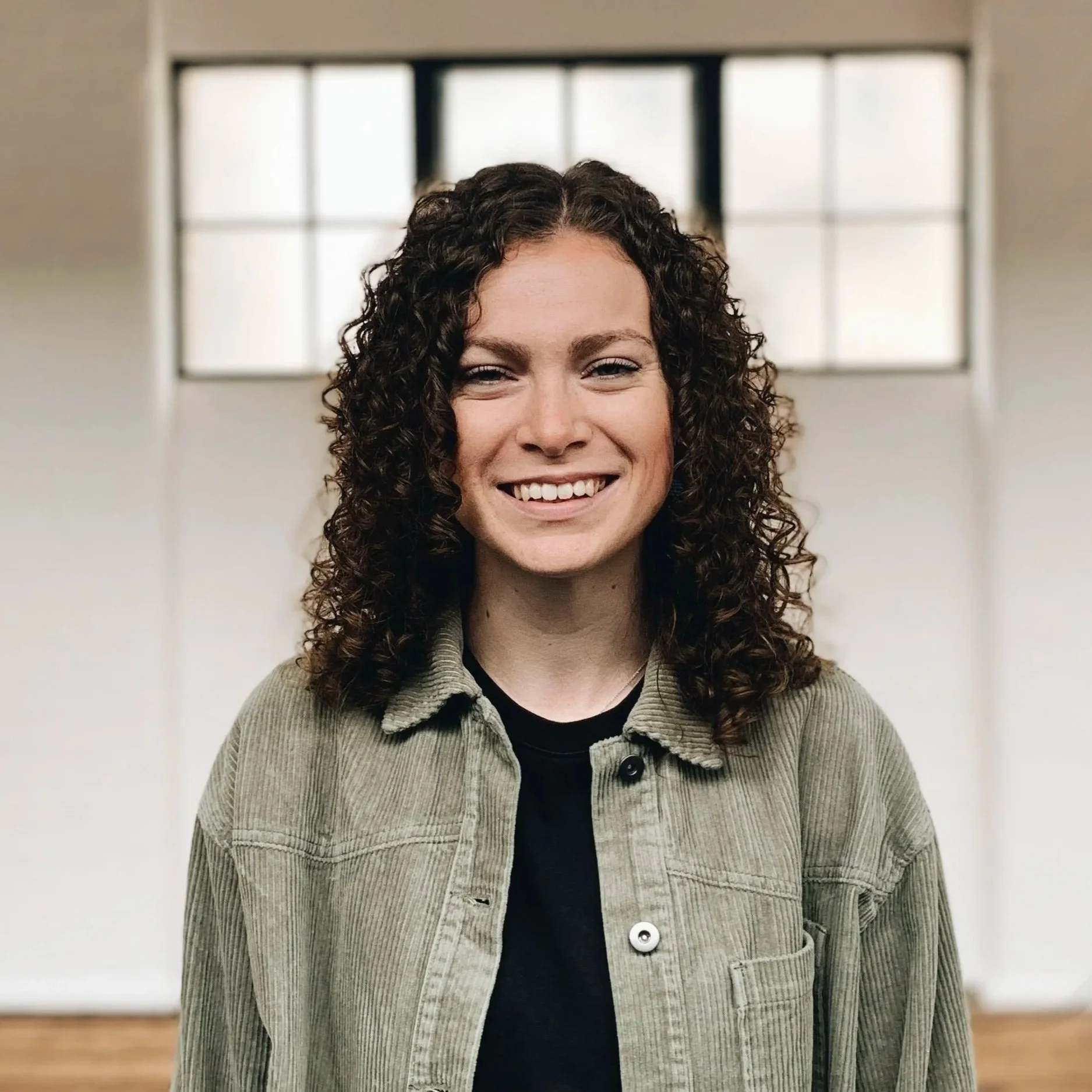 A smiling Hannah Grout standing in front of a wall.