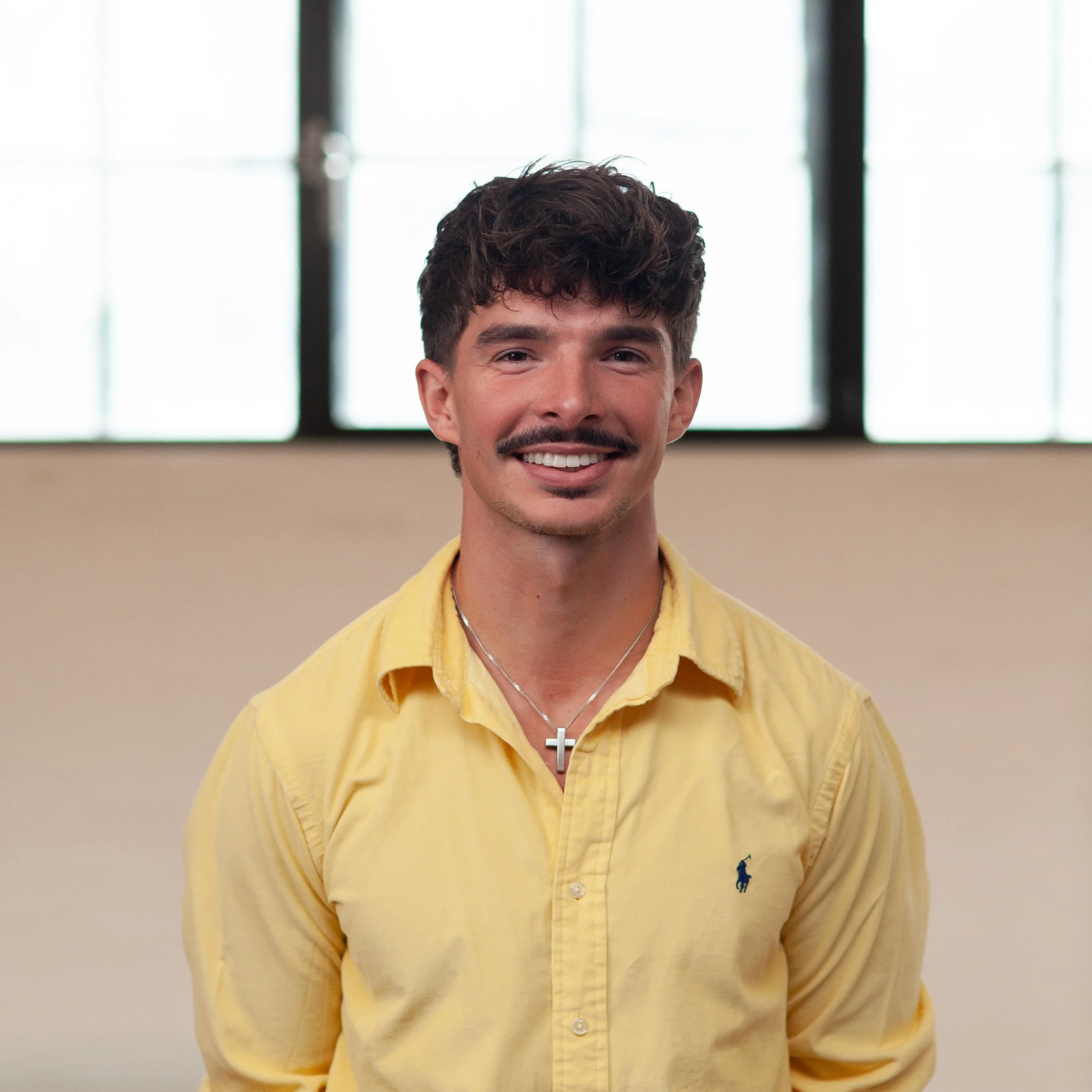 A smiling Ben Hallam standing in front of a wall.