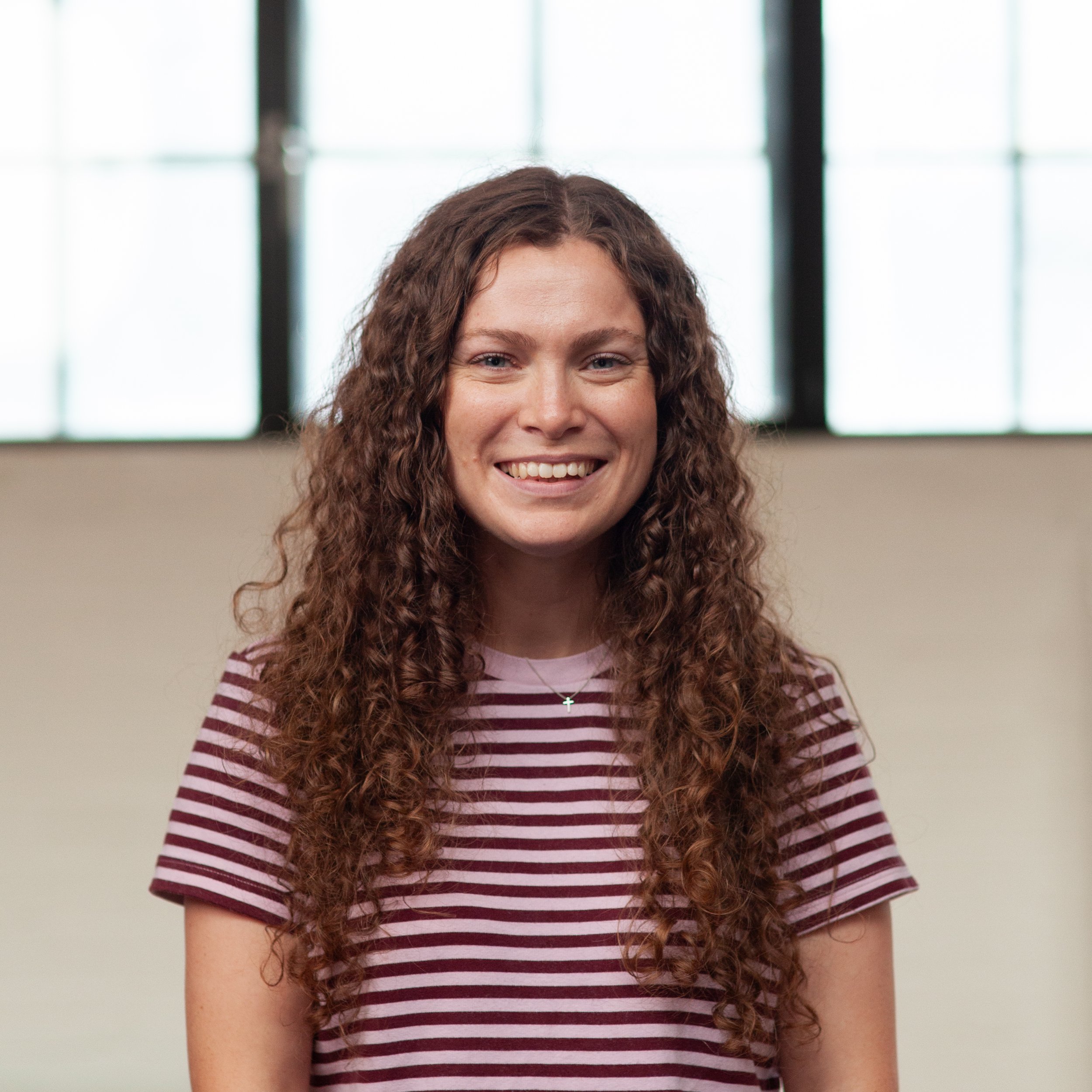A smiling Hannah Grout standing in front of a wall.