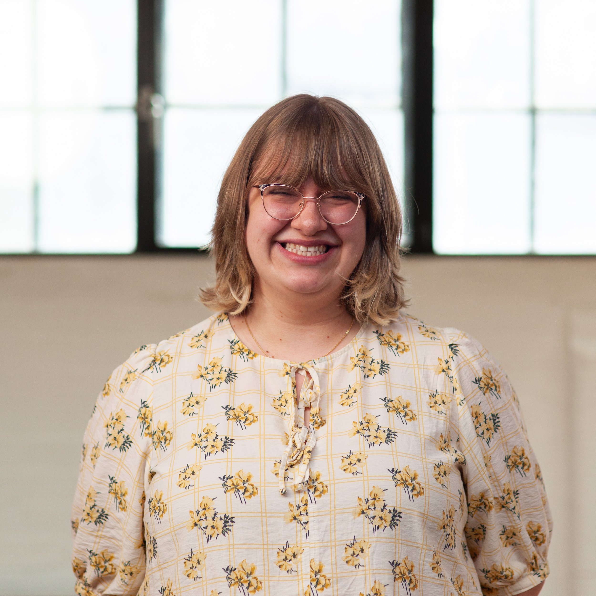 A smiling Grace Winnington standing in front of a wall.
