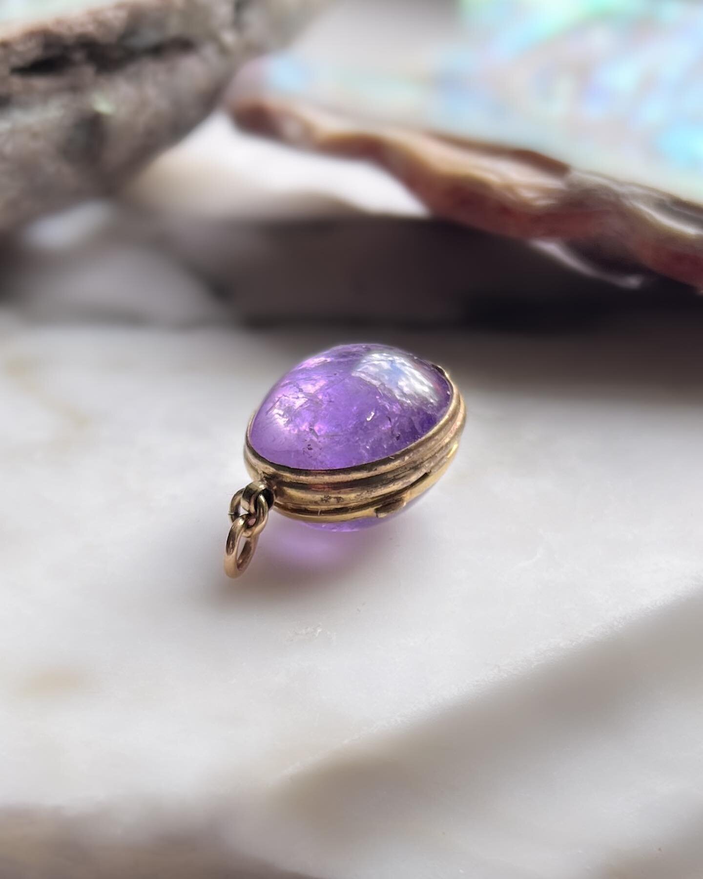19th c. oval or egg-shaped locket formed from a pair of amethyst cabochons mounted in a gold hinged gilt copper frame. There is a space between the stones when the locket is closed to hold a photograph or pressed flower keepsake. The gemstones are a 