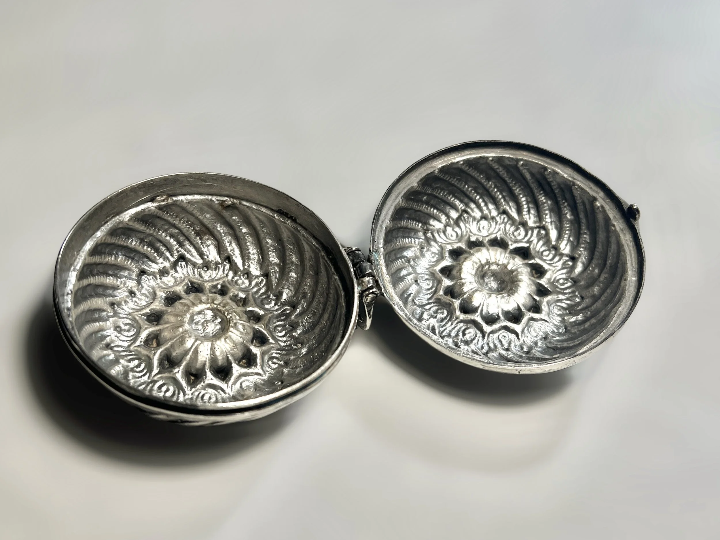 The interior of a chased indian silver round box