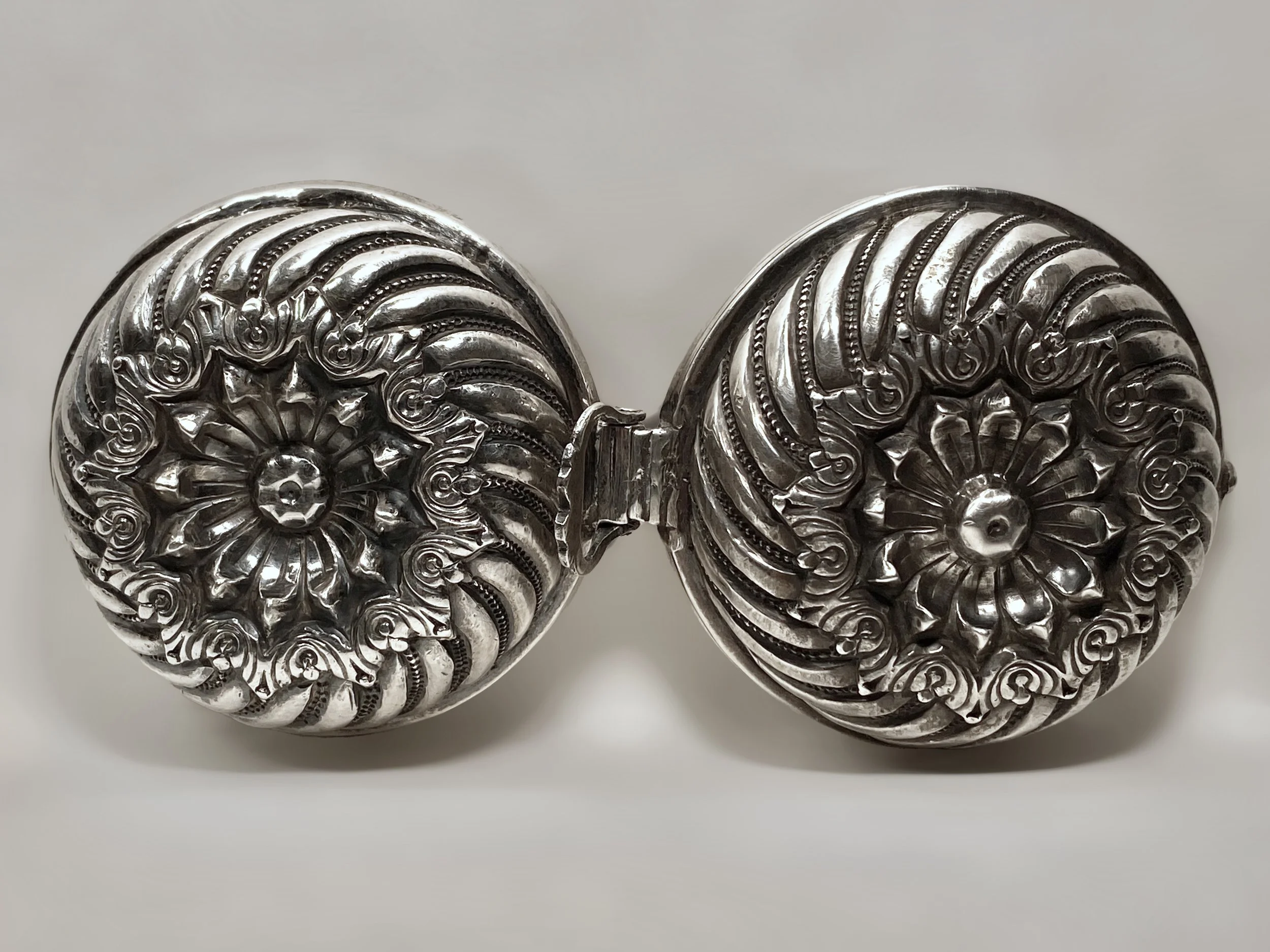 A silver Gujarat, Kutch, India silver box, opened with both halves of the chased silver designs visible.