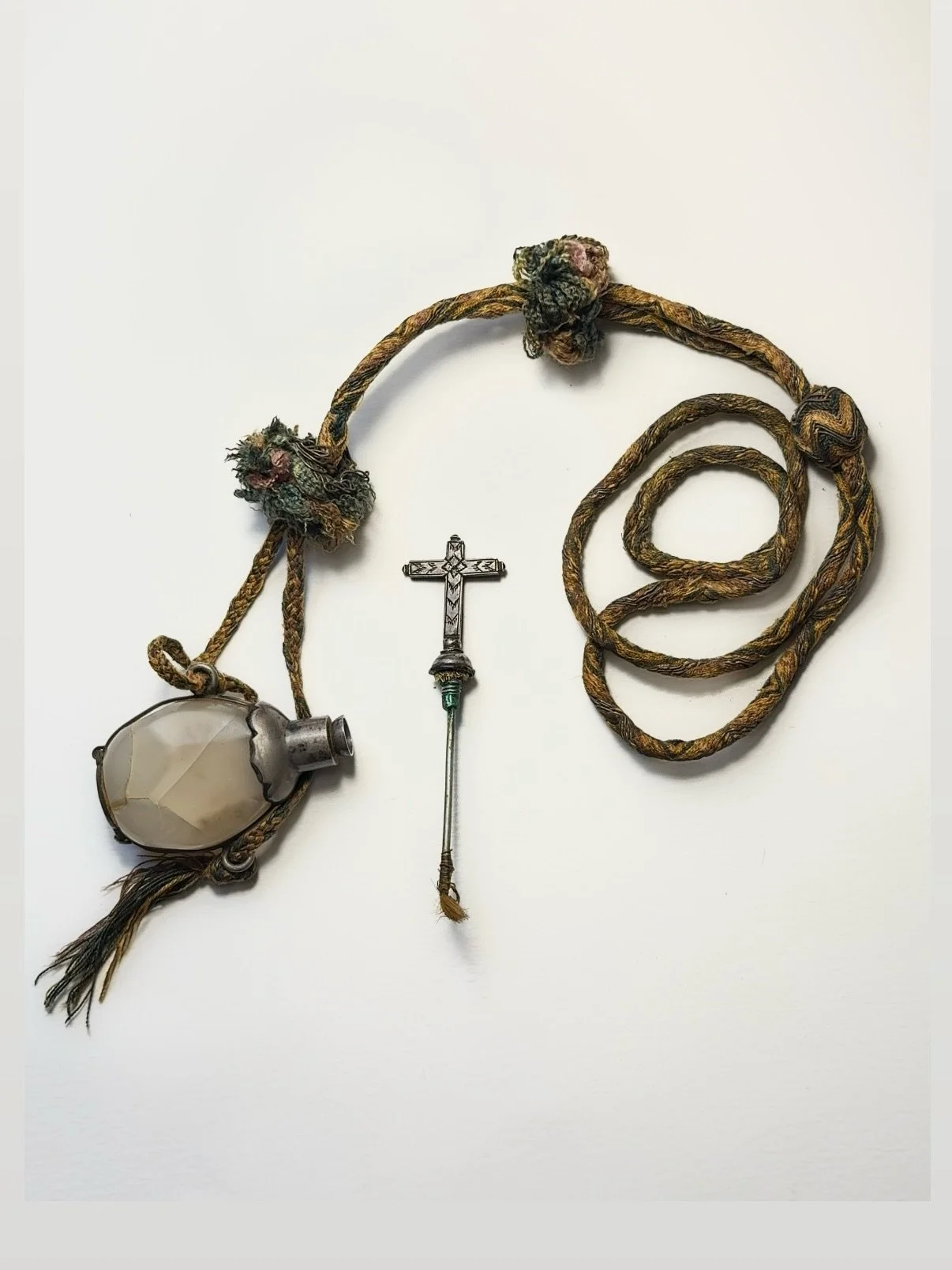 Available. Antique rock crystal pendant ampulla (anointing-oil flask), the faceted, well-hollowed crystal body in silver mounts with cross-finial and internal brush for holy oil.
Originally worn like a necklace, suspended from a braided cord of multi