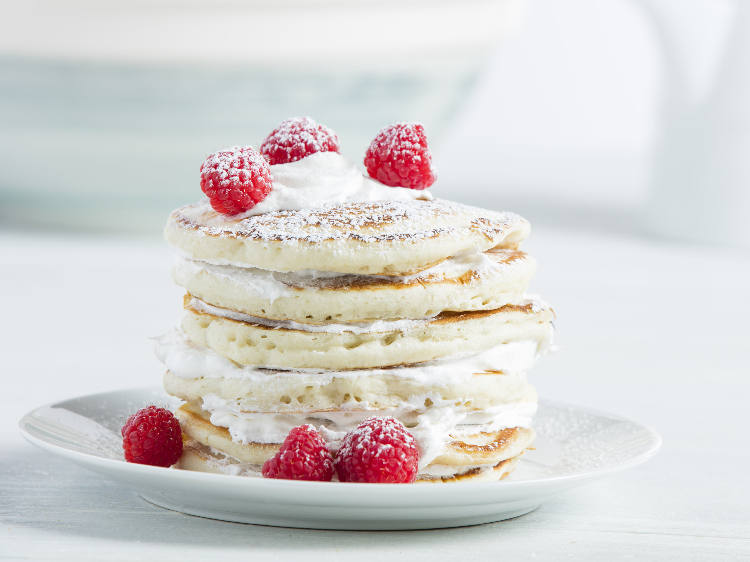 Stack of pancakes with raspberries in white kitchen