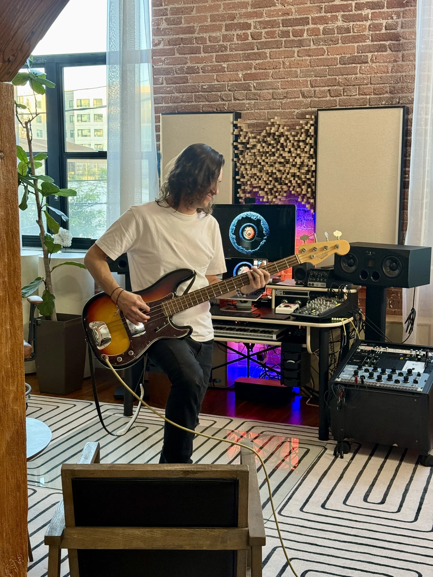 A seated guitarist playing in front of the studio monitors