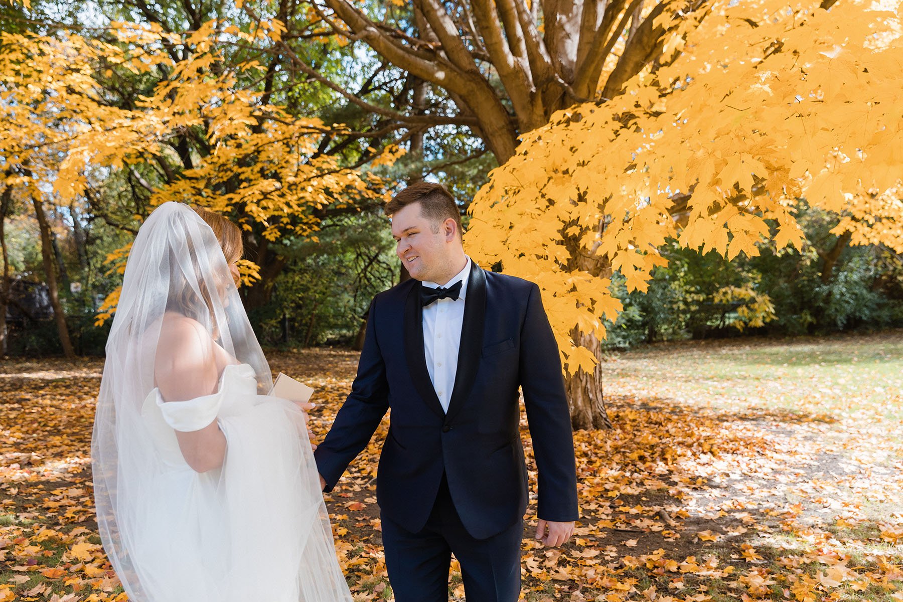 First look for bride and groom against orange fall leaves